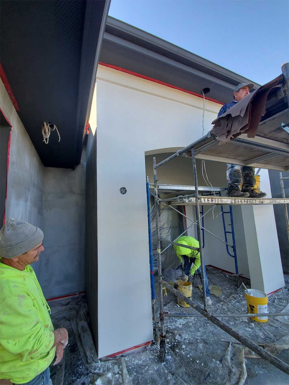A man in a yellow shirt is standing in front of a building under construction.
