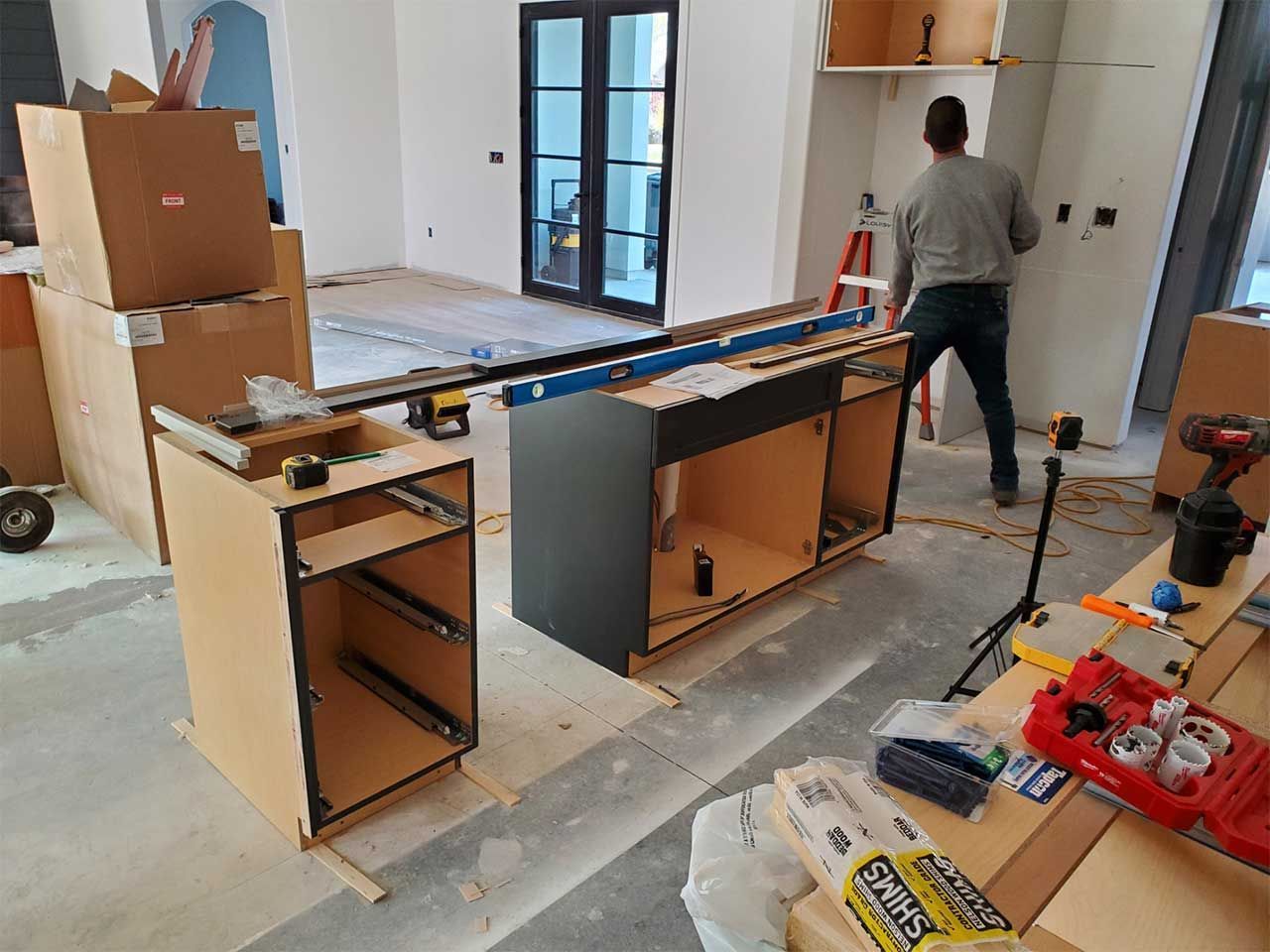 A man is working on a kitchen in a house under construction.