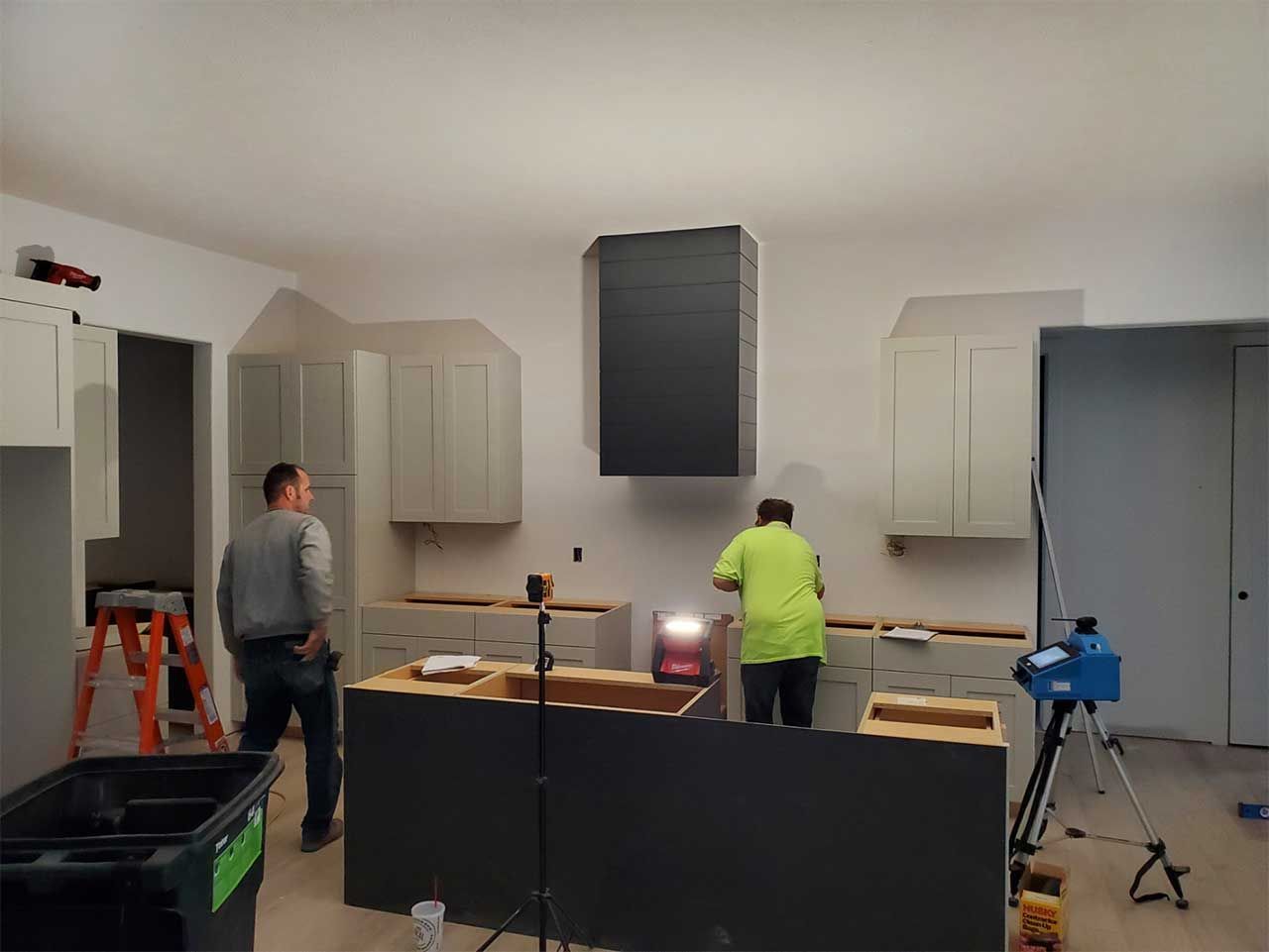A group of men are working on a kitchen in a house.