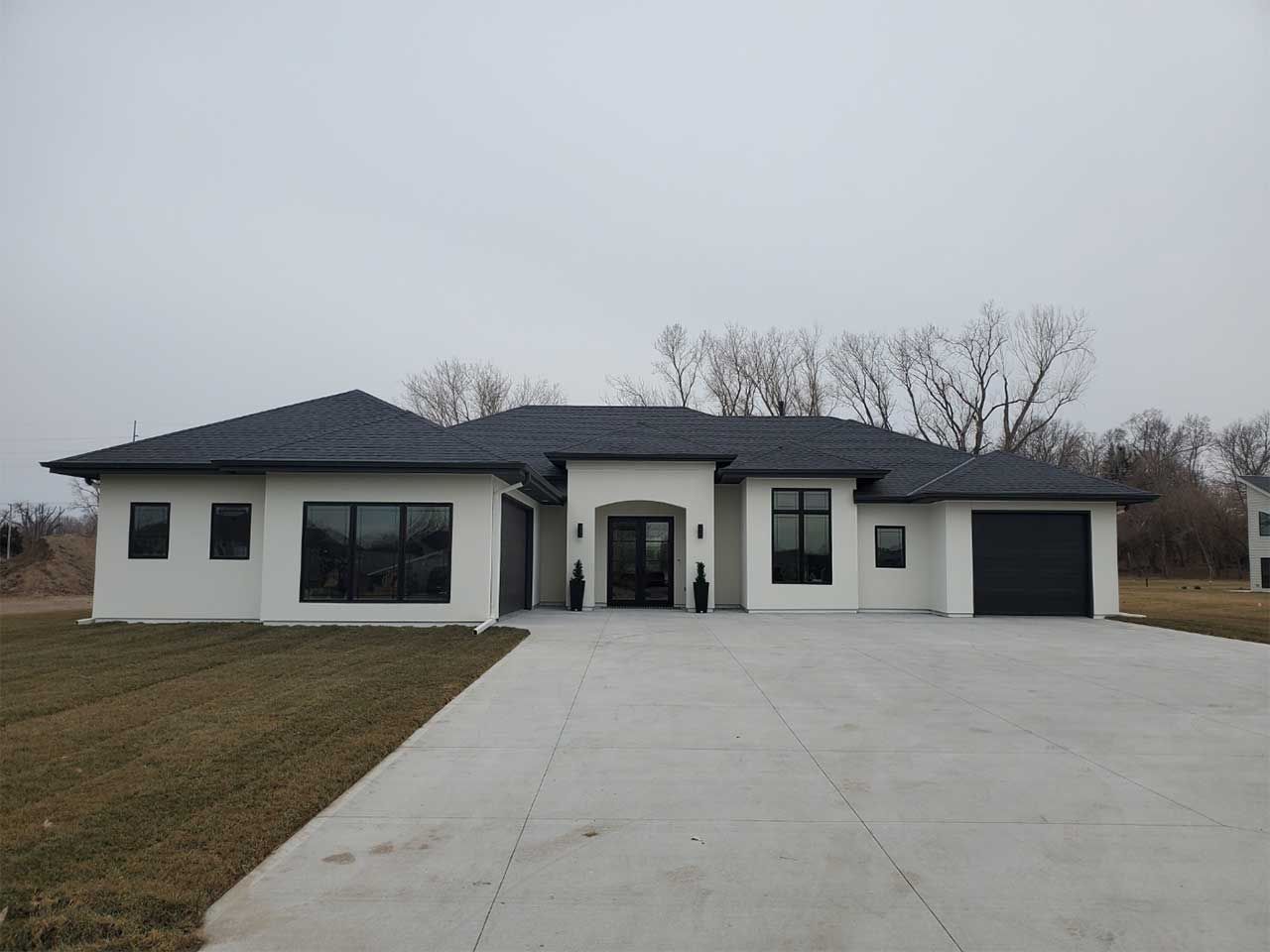 A large white house with a black roof and a concrete driveway.
