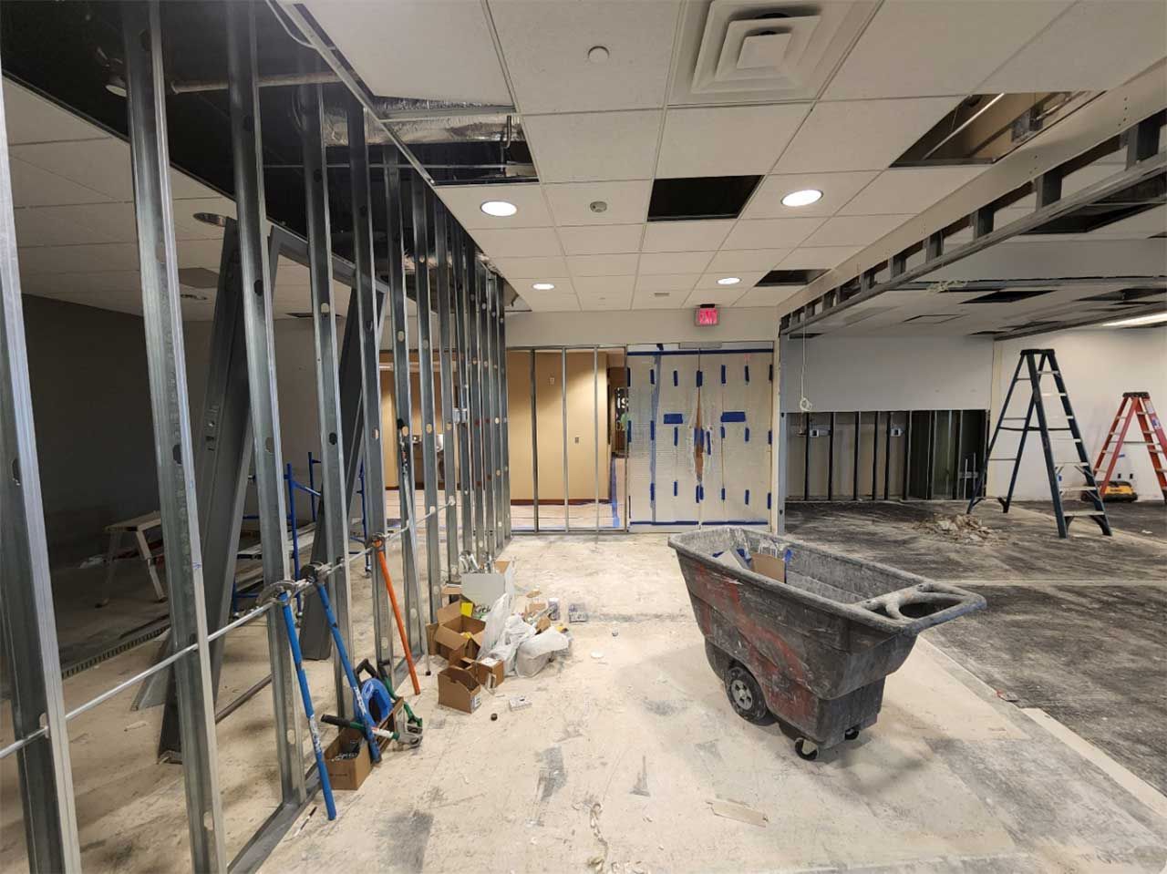 A building under construction with a wheelbarrow in the middle of the room.