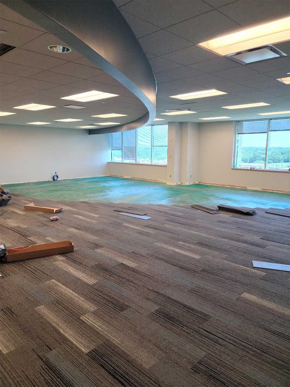 A large empty room with a carpeted floor and a lot of windows.