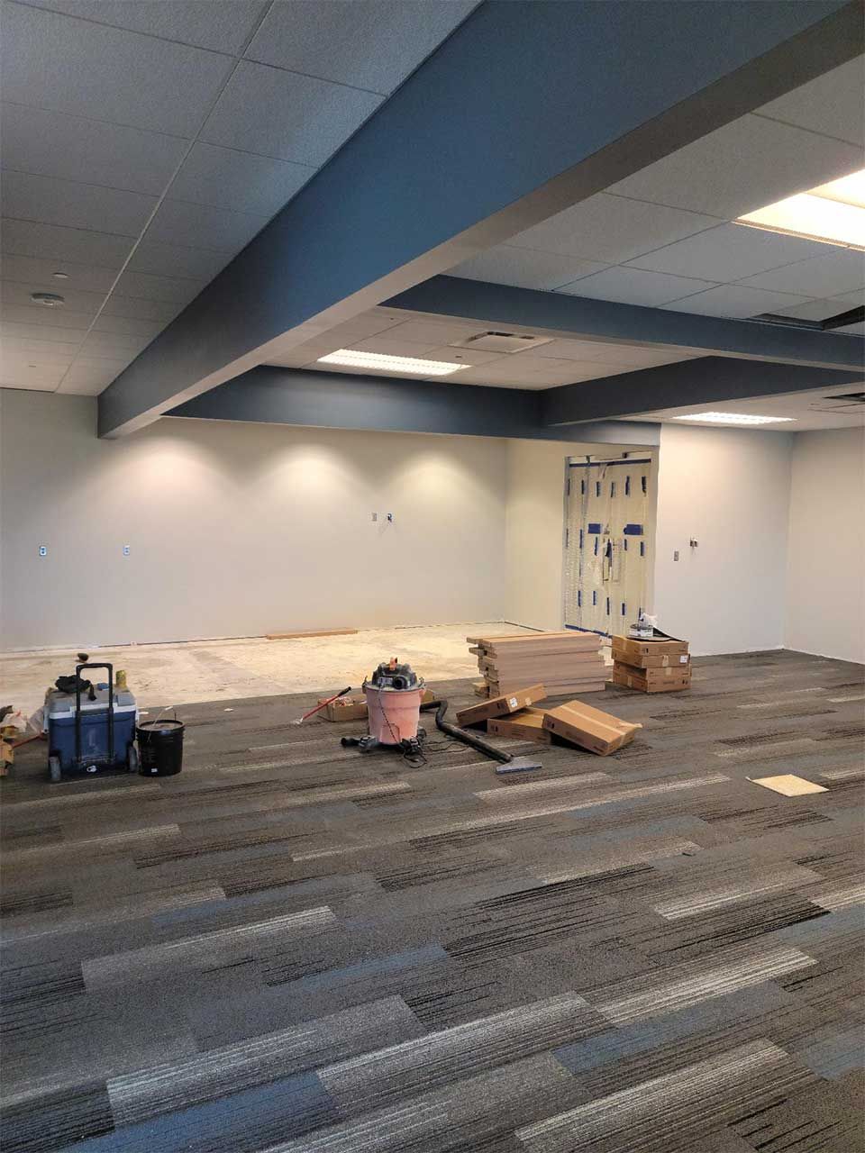 An empty room with a vacuum cleaner and boxes on the floor.