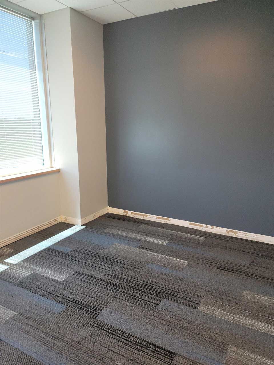 An empty room with a carpeted floor and a window.