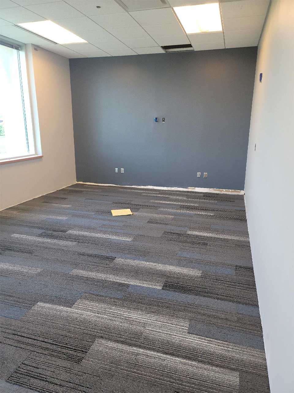 An empty room with a carpeted floor and a window.