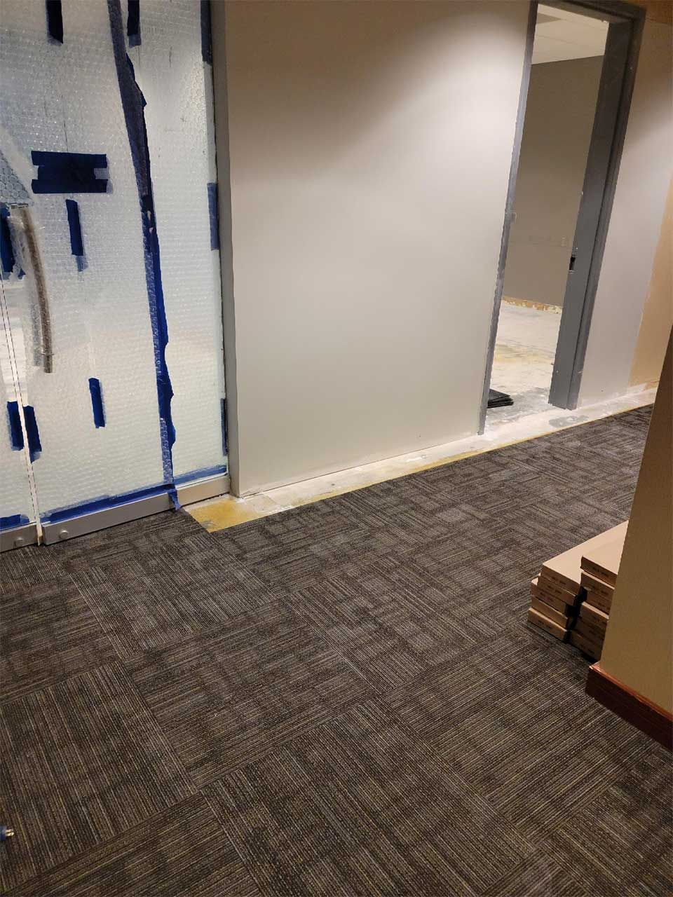 A hallway with a carpeted floor and a glass door.