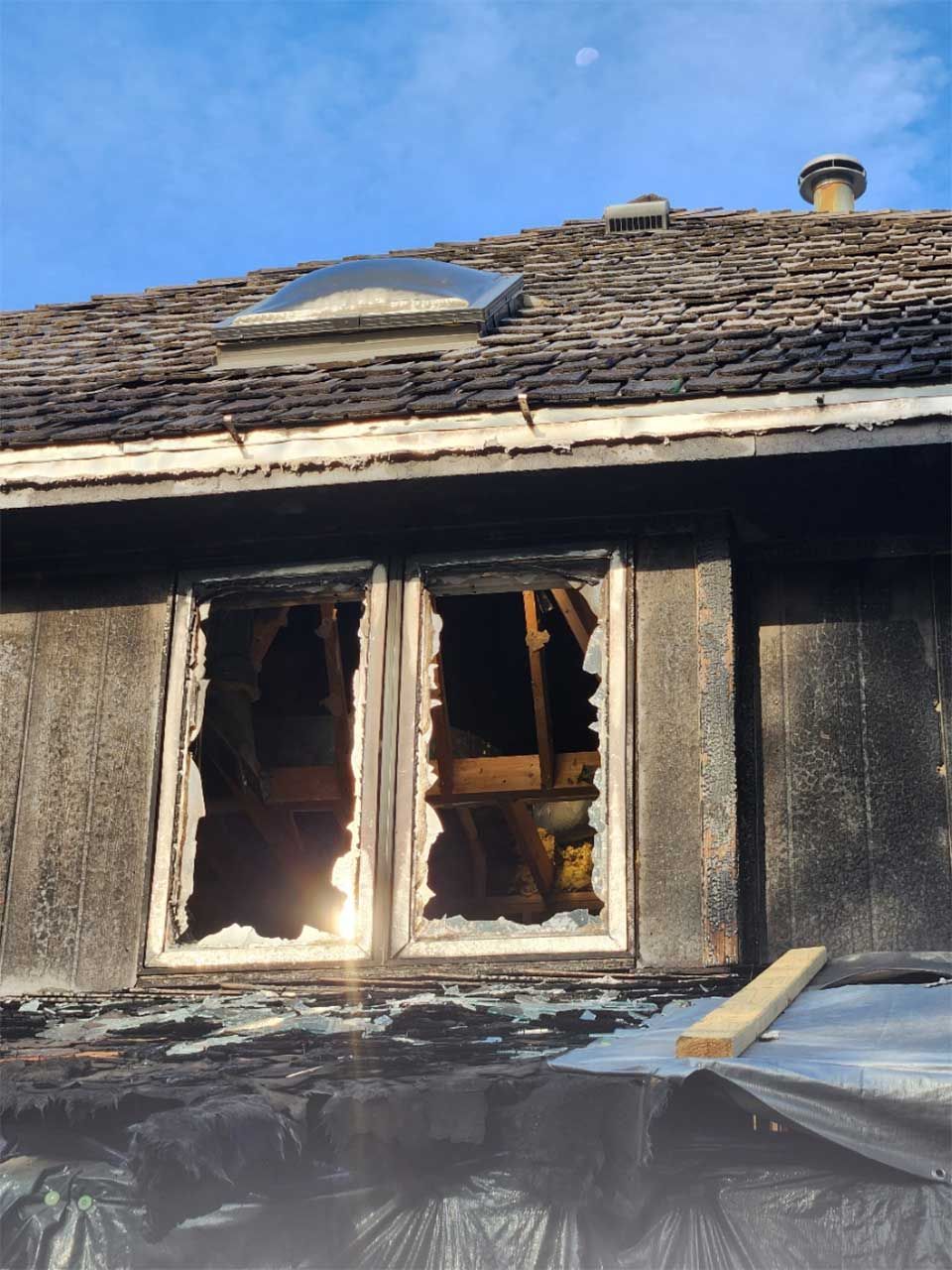 A house with two broken windows and a skylight on the roof