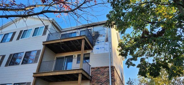 A large apartment building with a balcony and a tree in front of it.