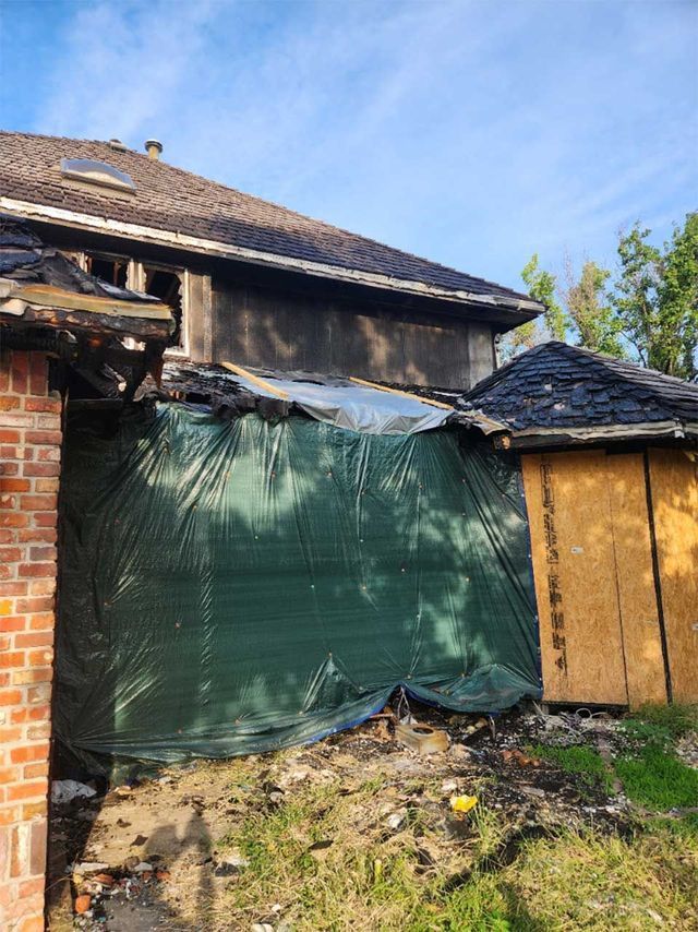 A brick house with a green tarp on the side of it.