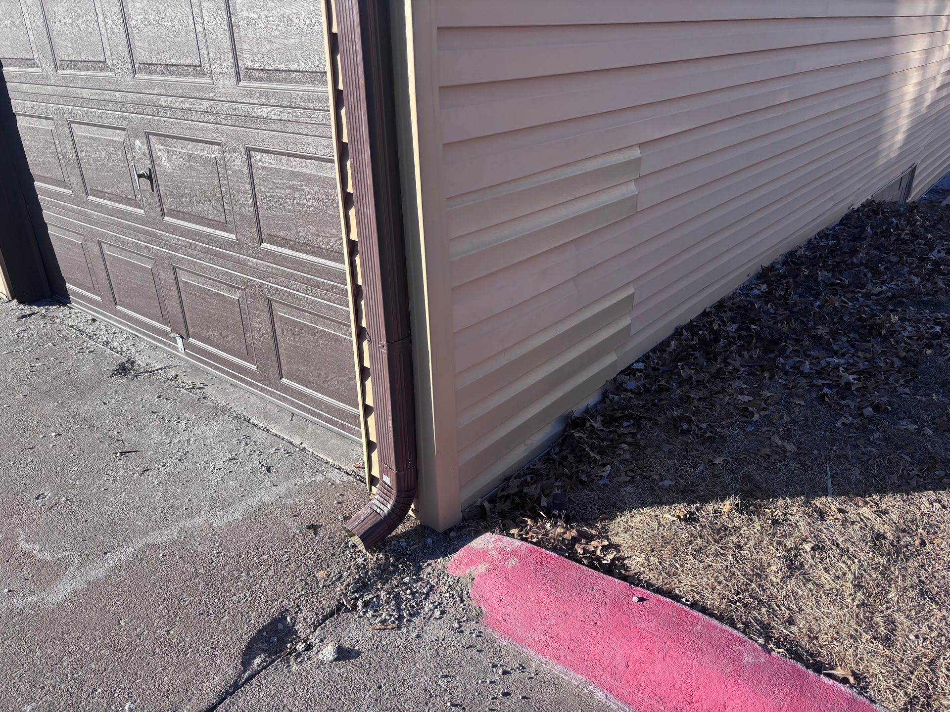 A pink curb is next to a garage door