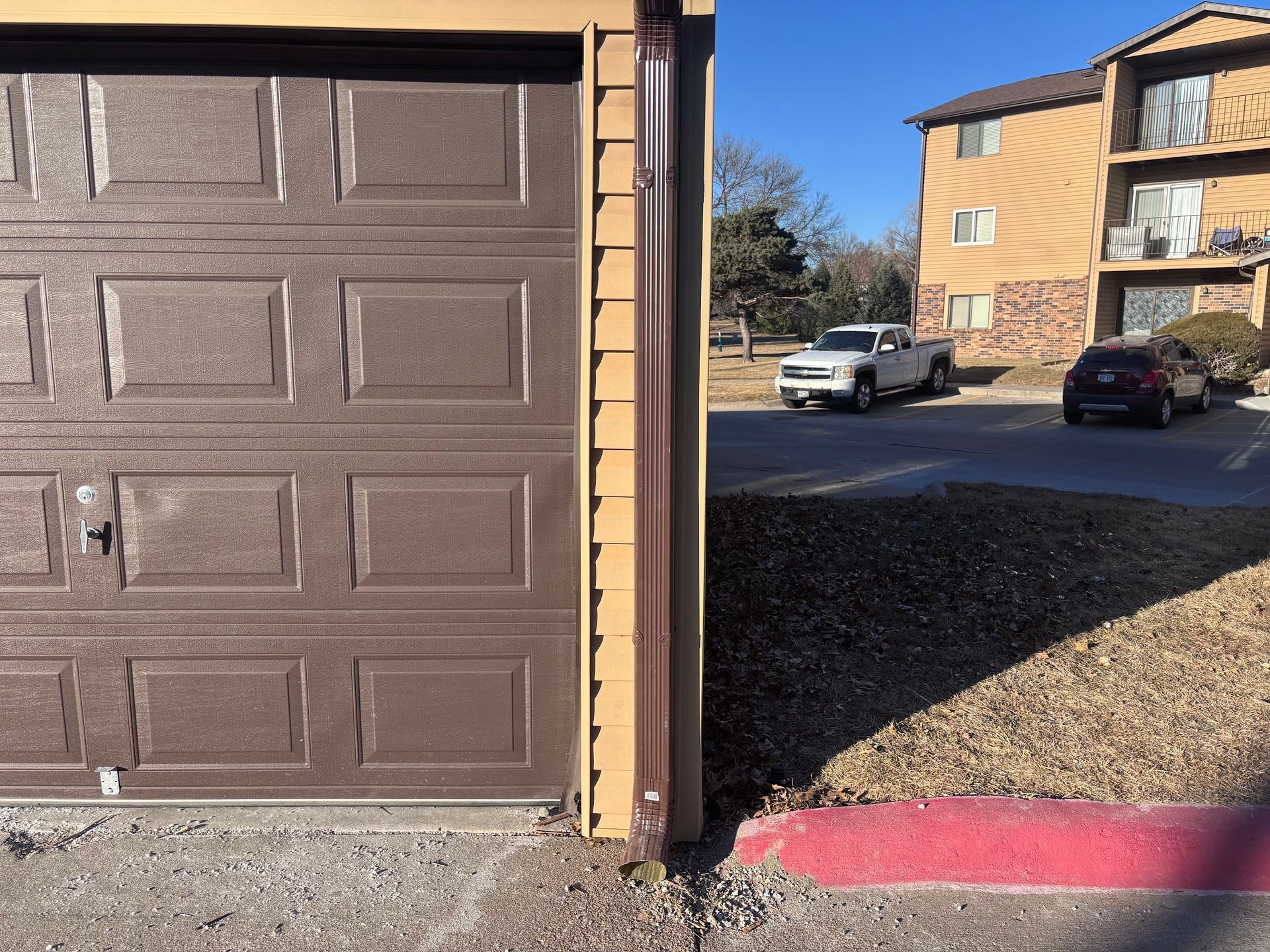 A brown garage door with a white truck parked in front of it
