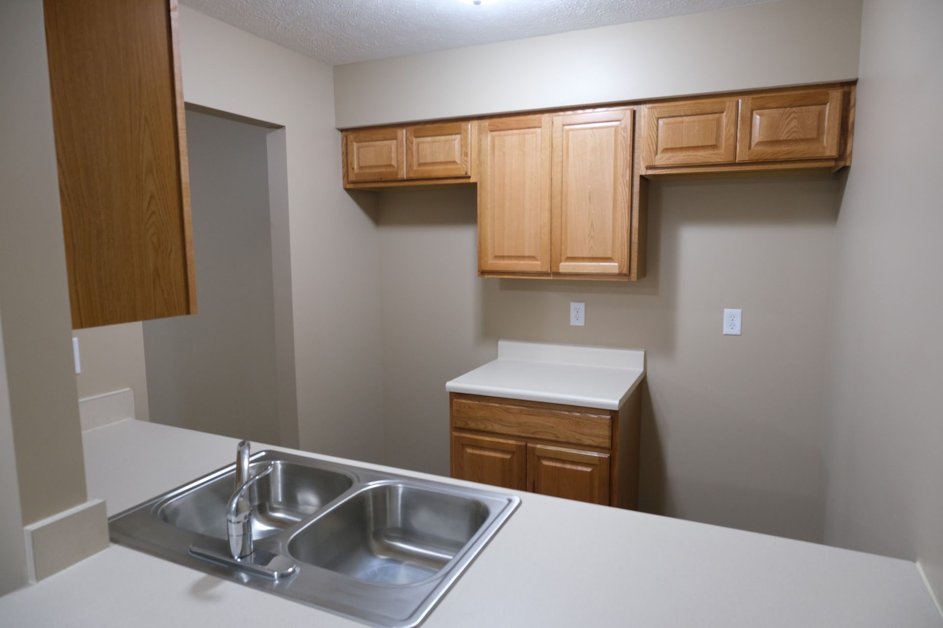 A kitchen with stainless steel sink and wooden cabinets
