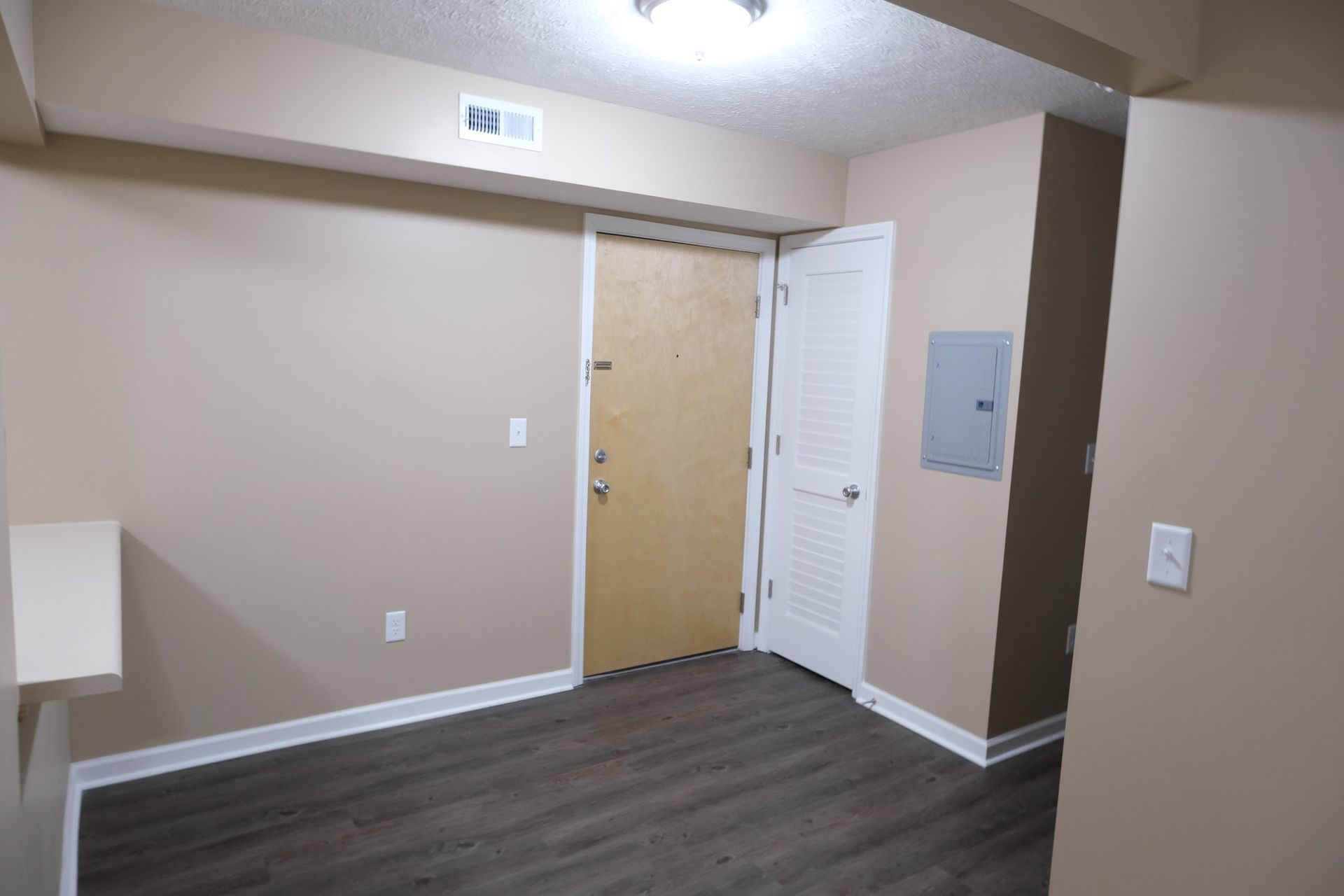 An empty room with a door and a light switch on the wall.