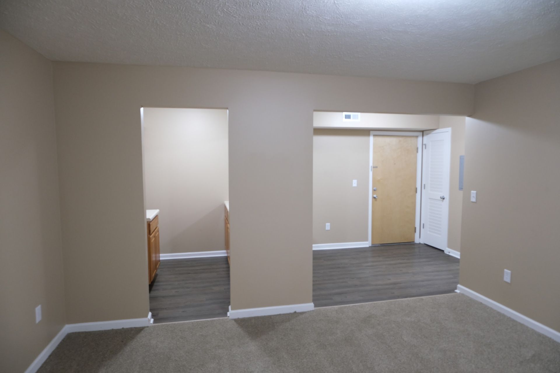 An empty room with a carpeted floor and beige walls.