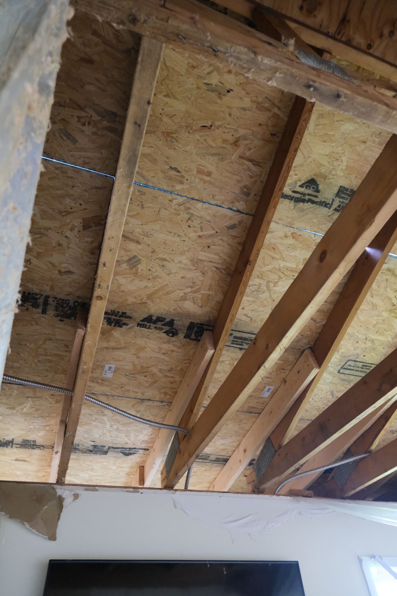 View from below of a wood-framed ceiling with OSB sheathing.
