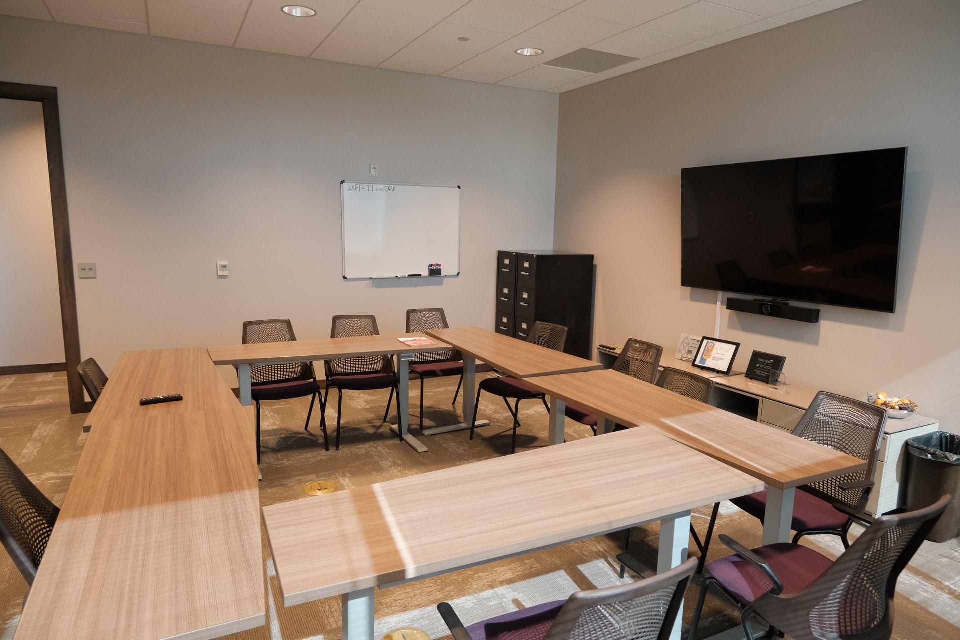A conference room with tables and chairs and a flat screen tv.