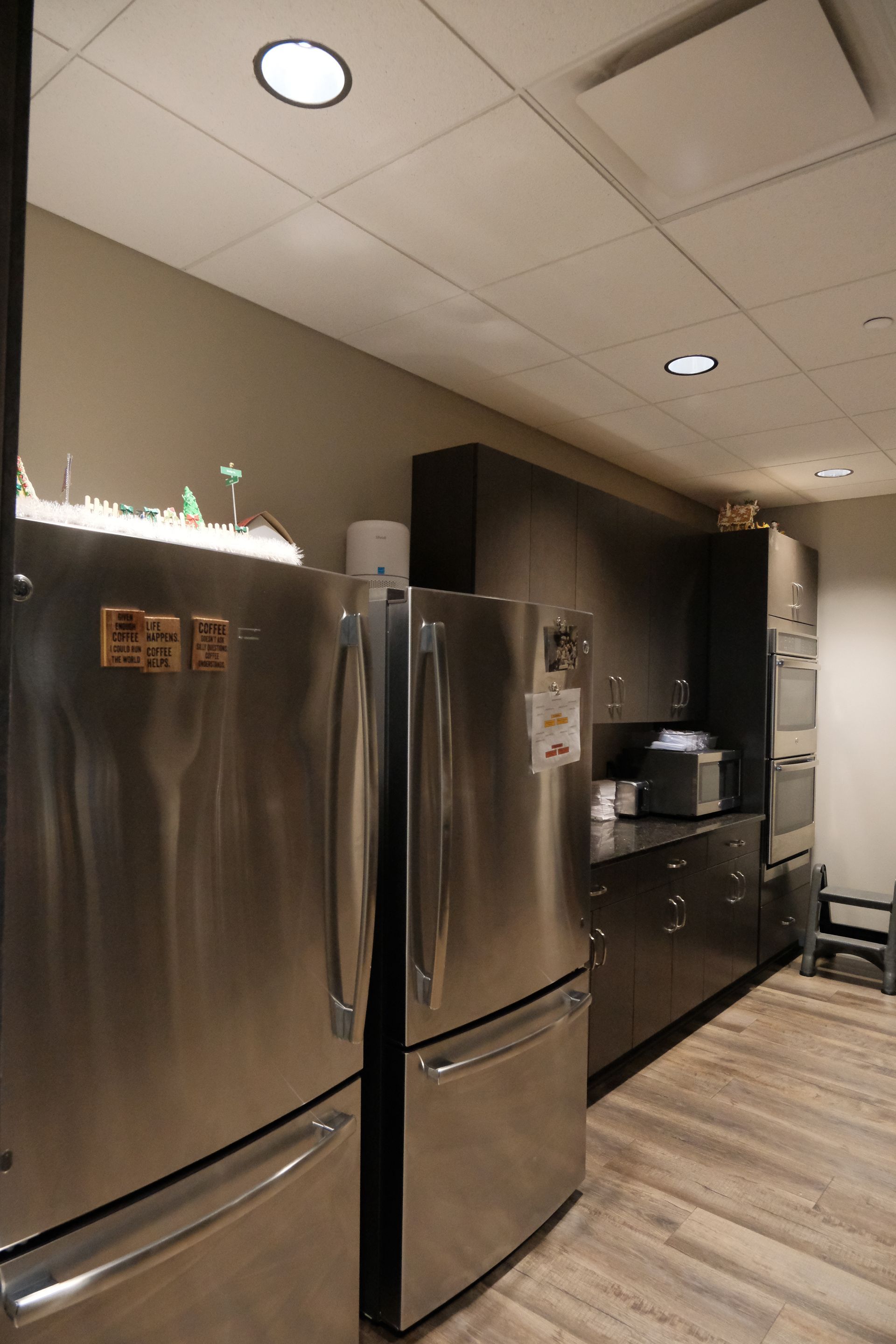 A kitchen with two stainless steel refrigerators and a microwave.