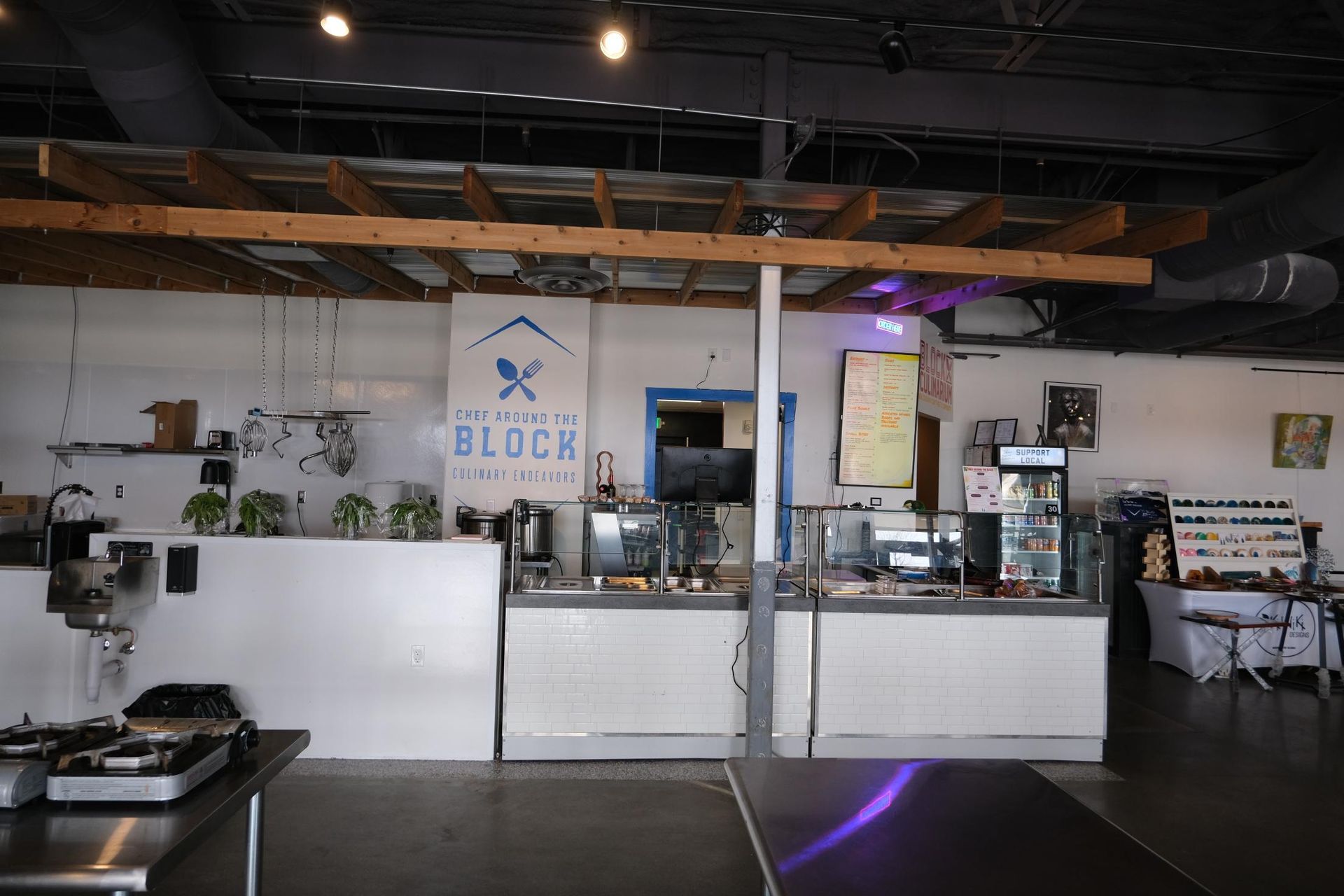 An indoor view of a restaurant food service counter with white cabinetry, a wooden overhead trellis, and branding.