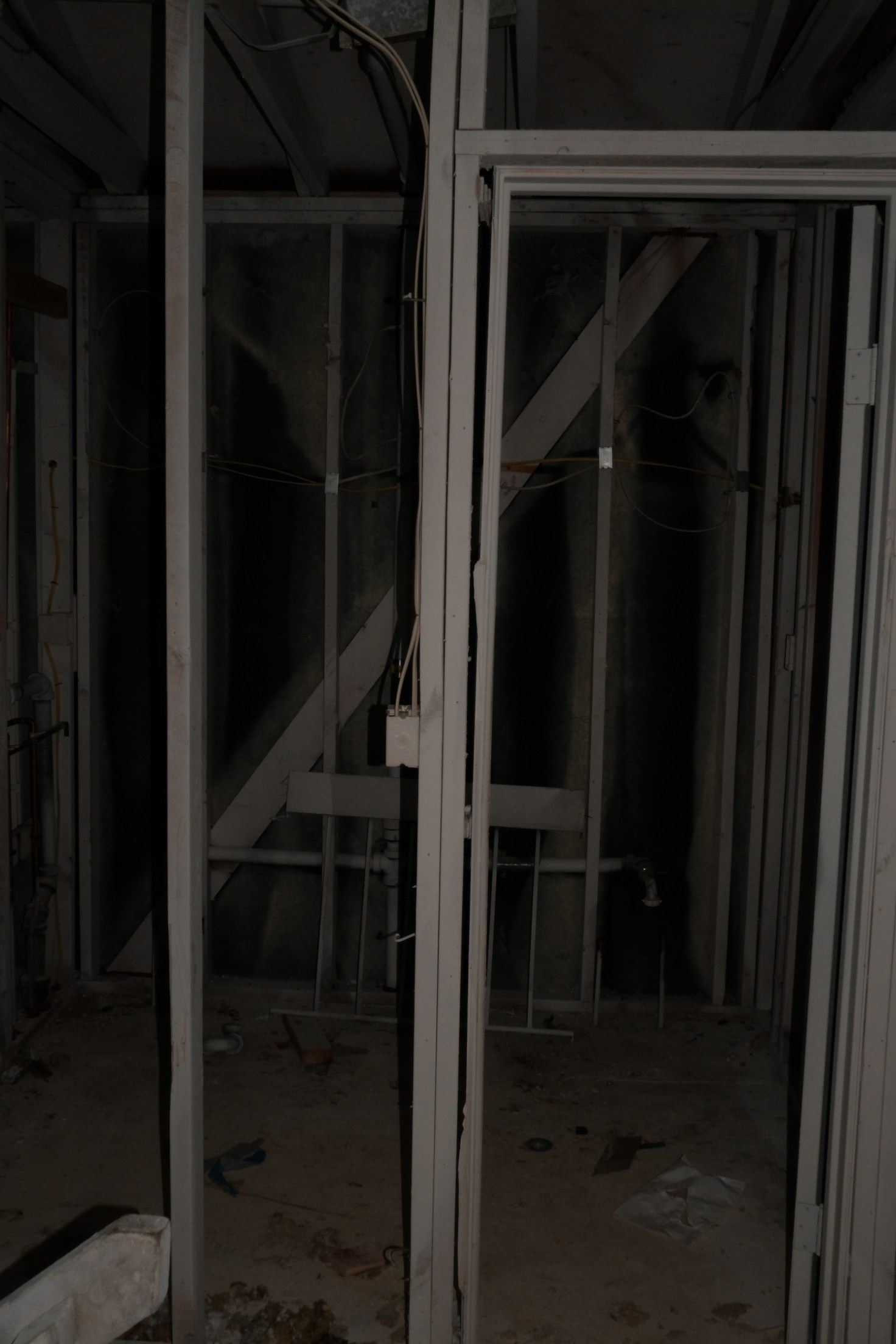 Gray metal door frame and support beams in a dimly lit, unfinished room.