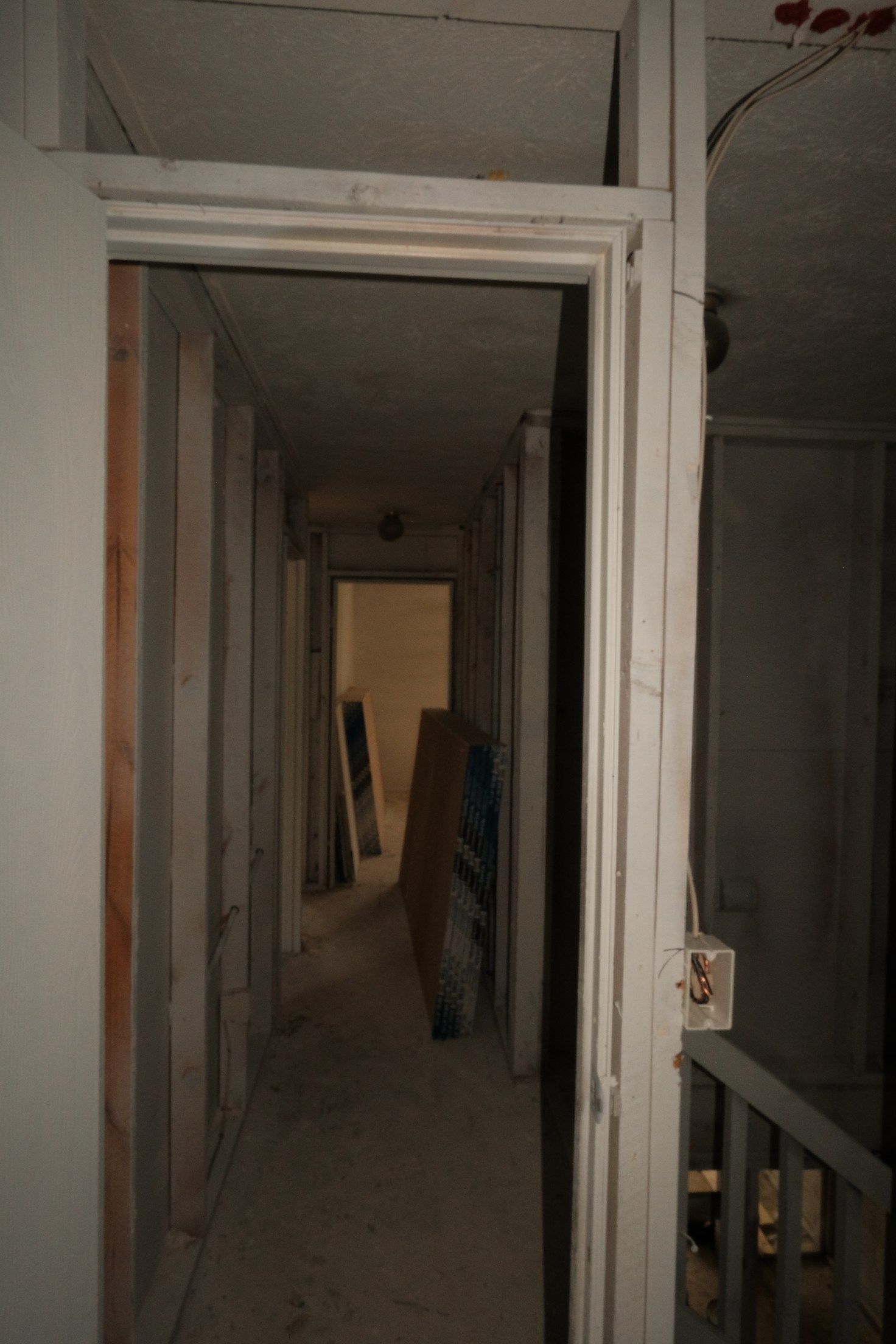 Hallway with an open door, bare walls, and dim lighting.
