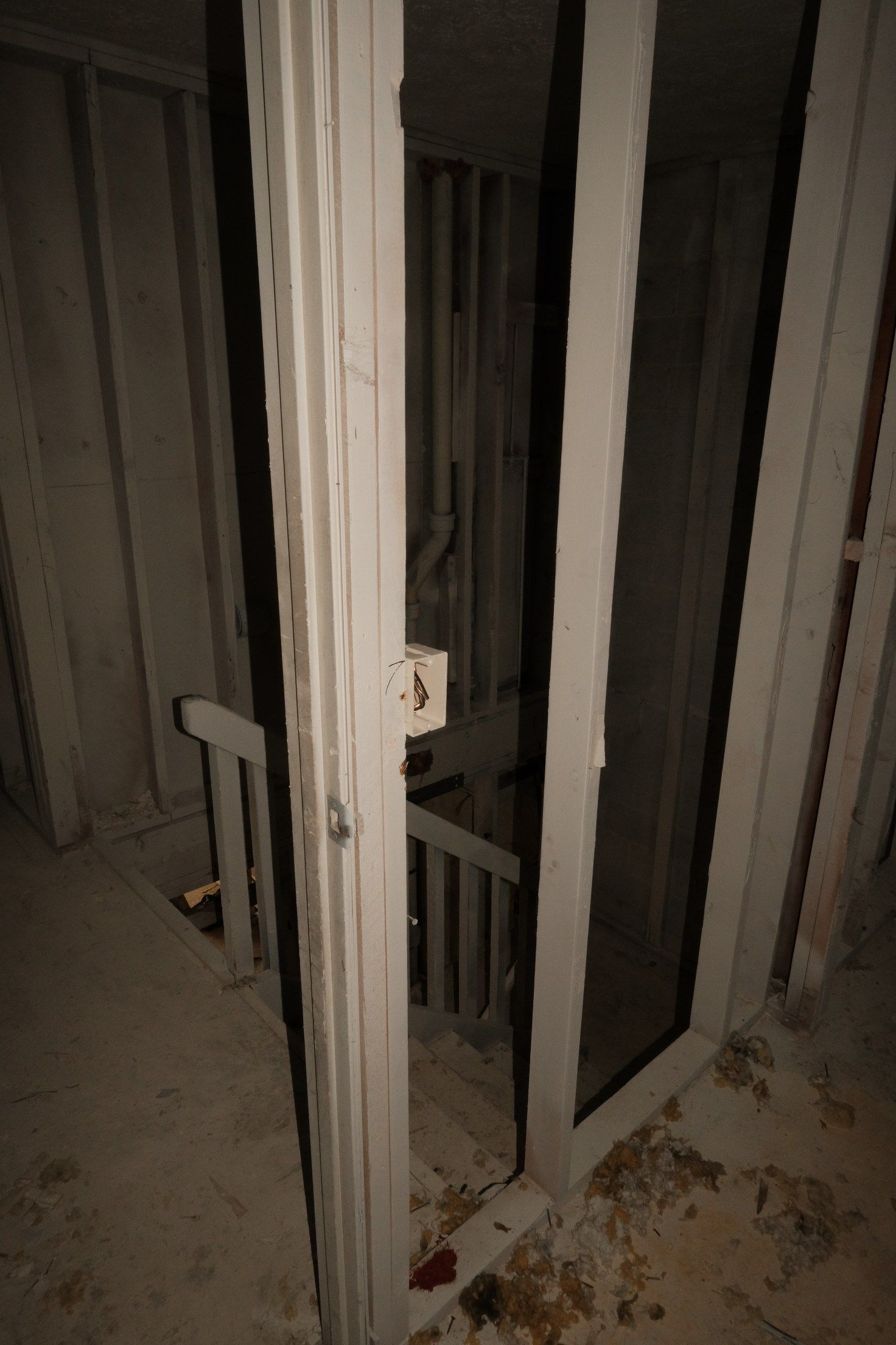 Staircase viewed through a white-framed doorway. The stairs lead down into a dark space.