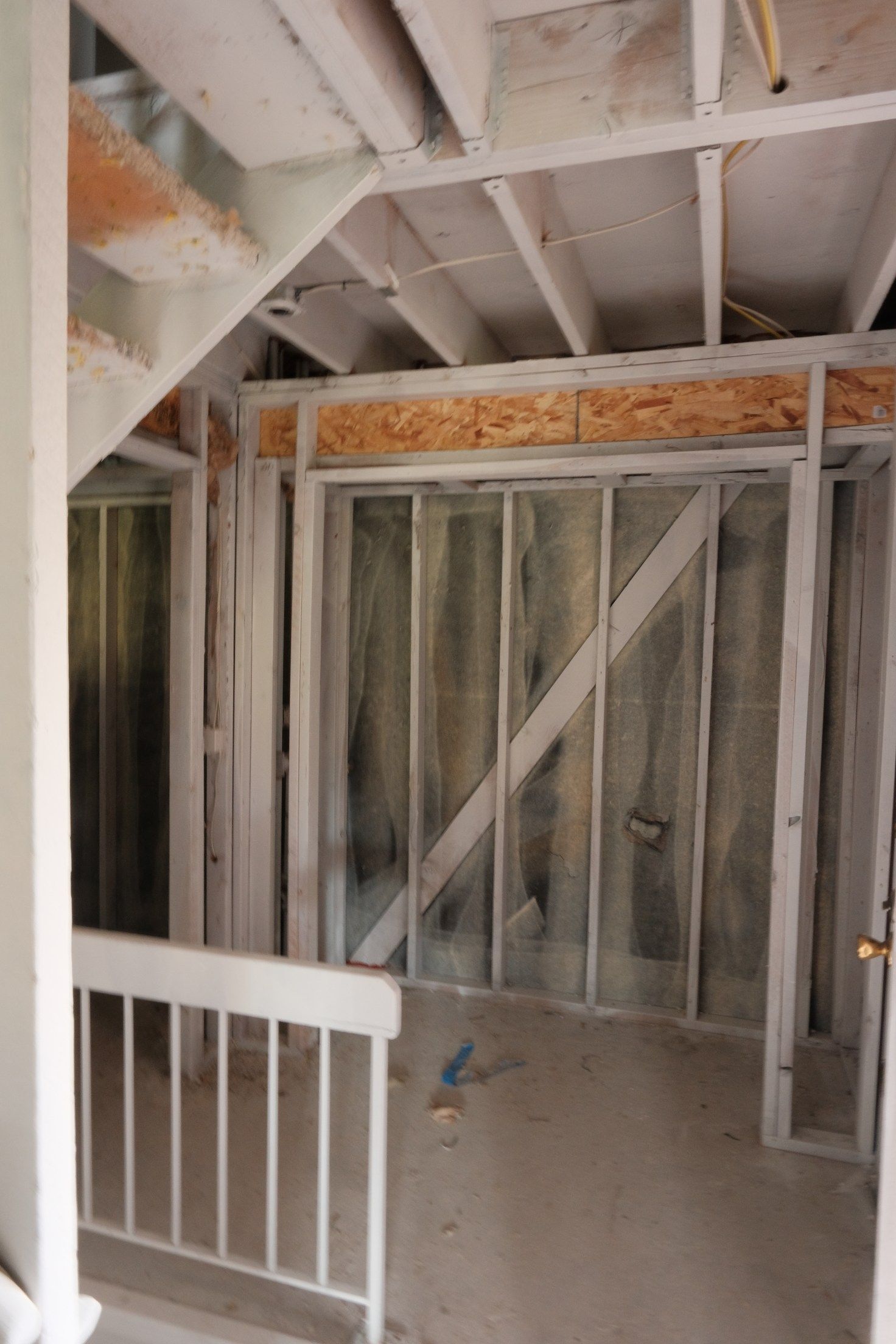 Interior view of unfinished construction, framing a doorway and a stairwell.