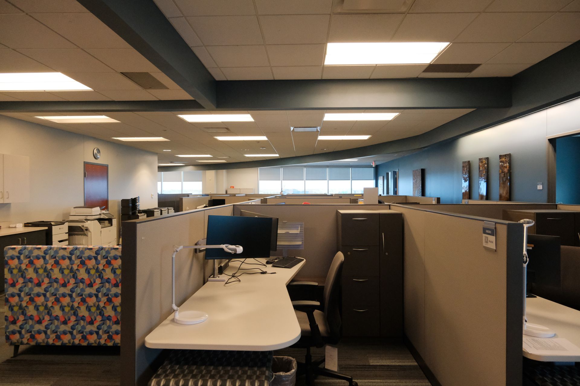 A large office with cubicles and a desk with a computer on it.