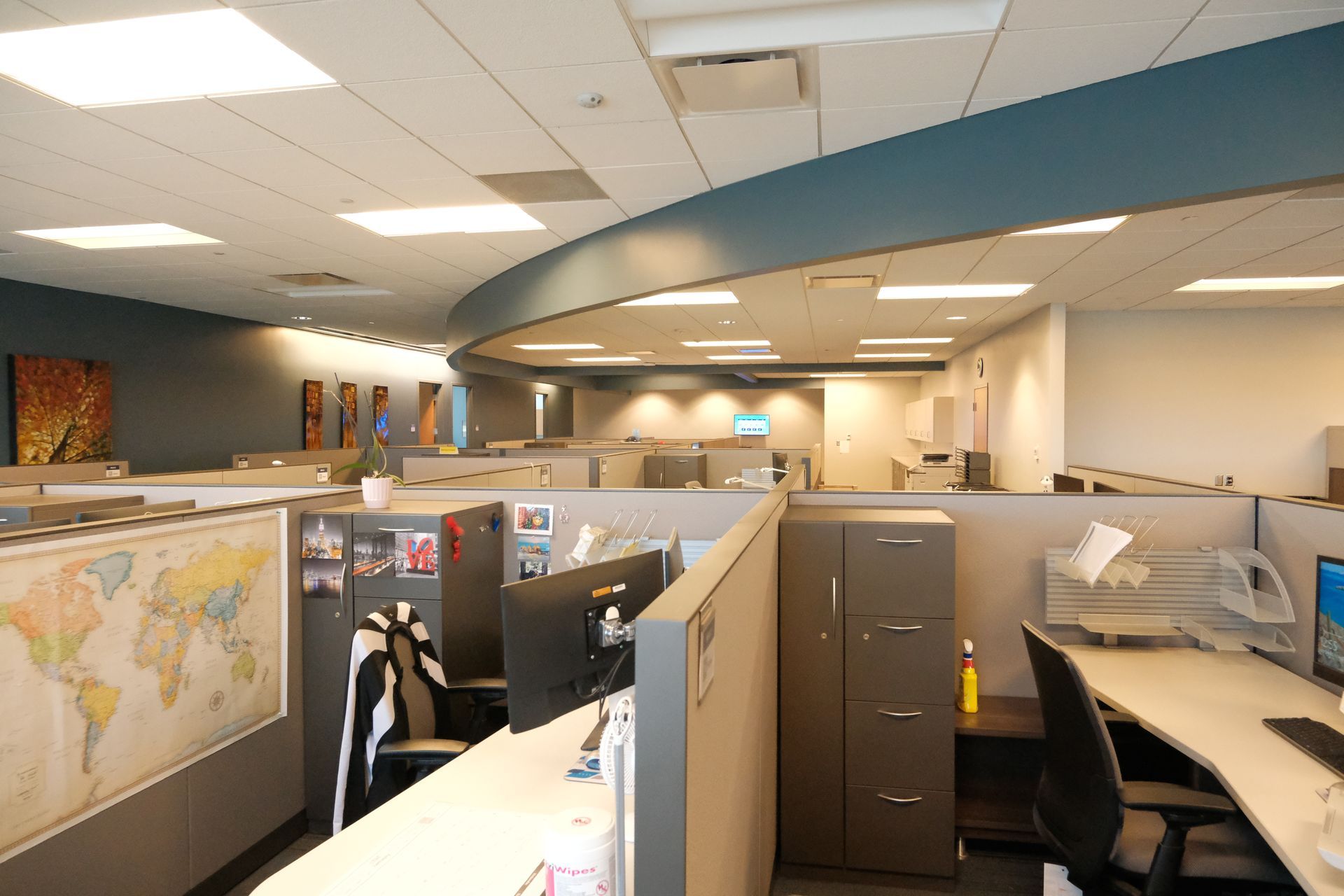 An office with cubicles and a map of the world on the wall