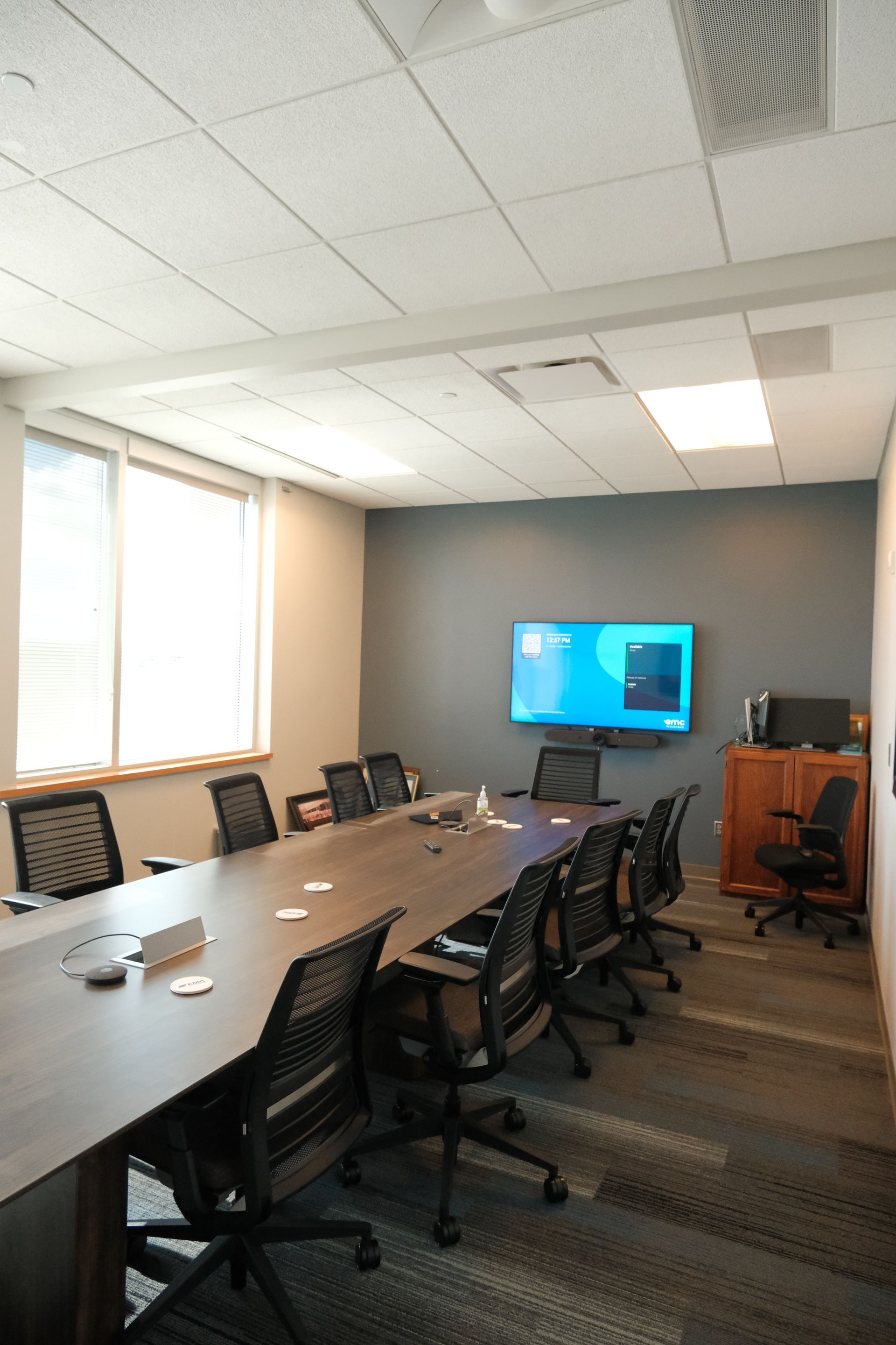 A conference room with a long table and chairs and a flat screen tv on the wall.