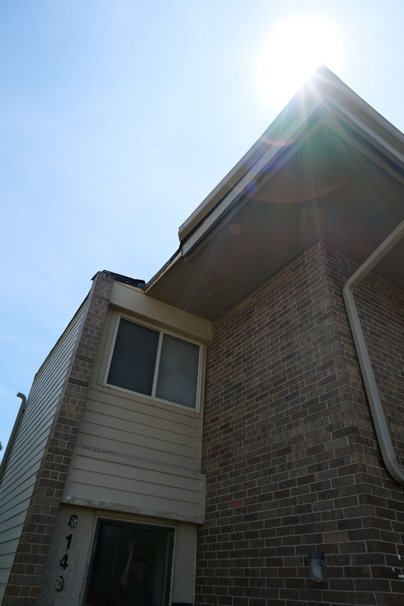 Low angle shot of a brick townhouse on a sunny day; address 6543 visible.