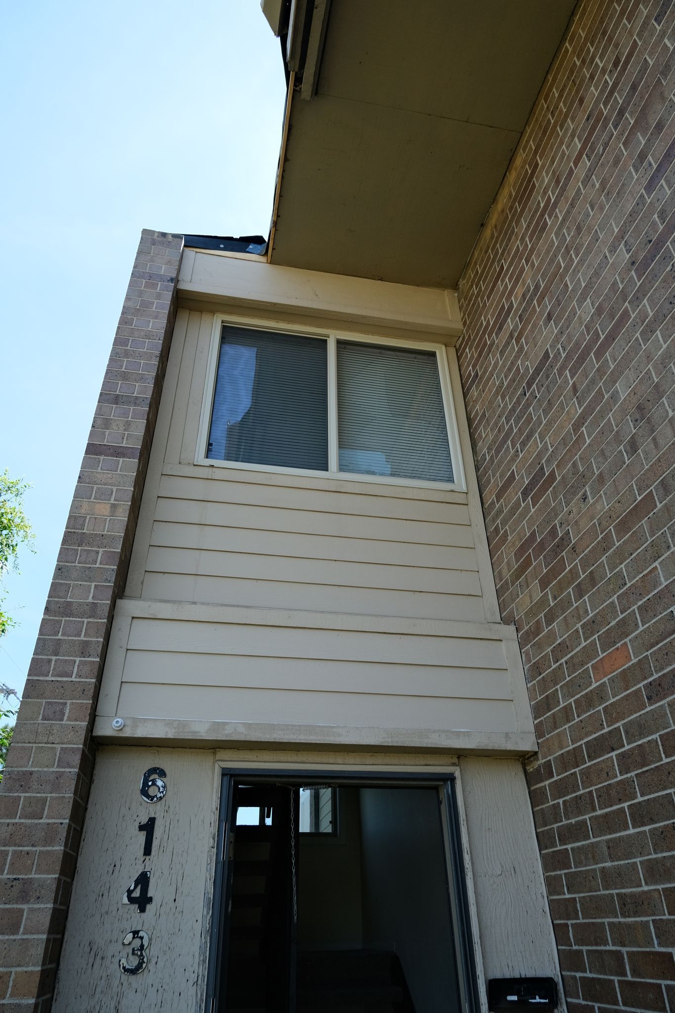 Apartment building exterior with a window, door, and brick and tan siding. The door has the number 643.