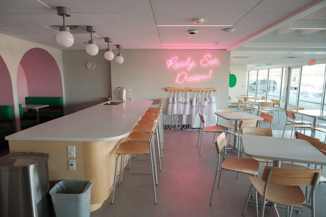 A restaurant with tables and chairs and a neon sign that says party on cream