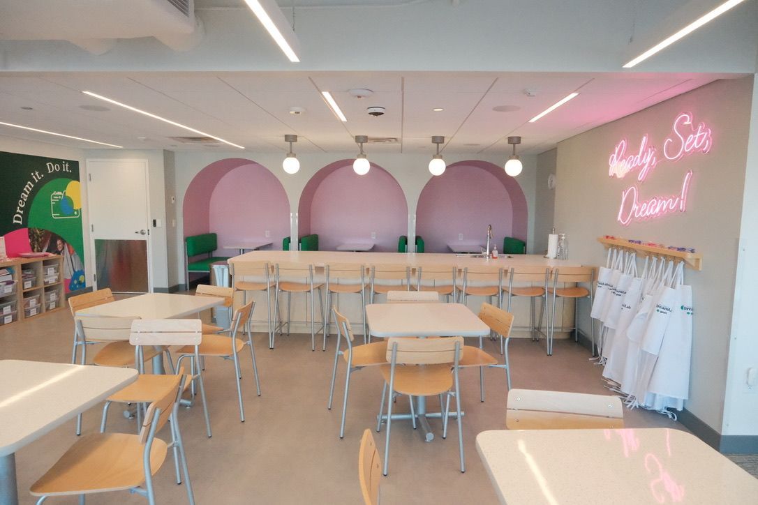 A restaurant with tables and chairs and a neon sign on the wall