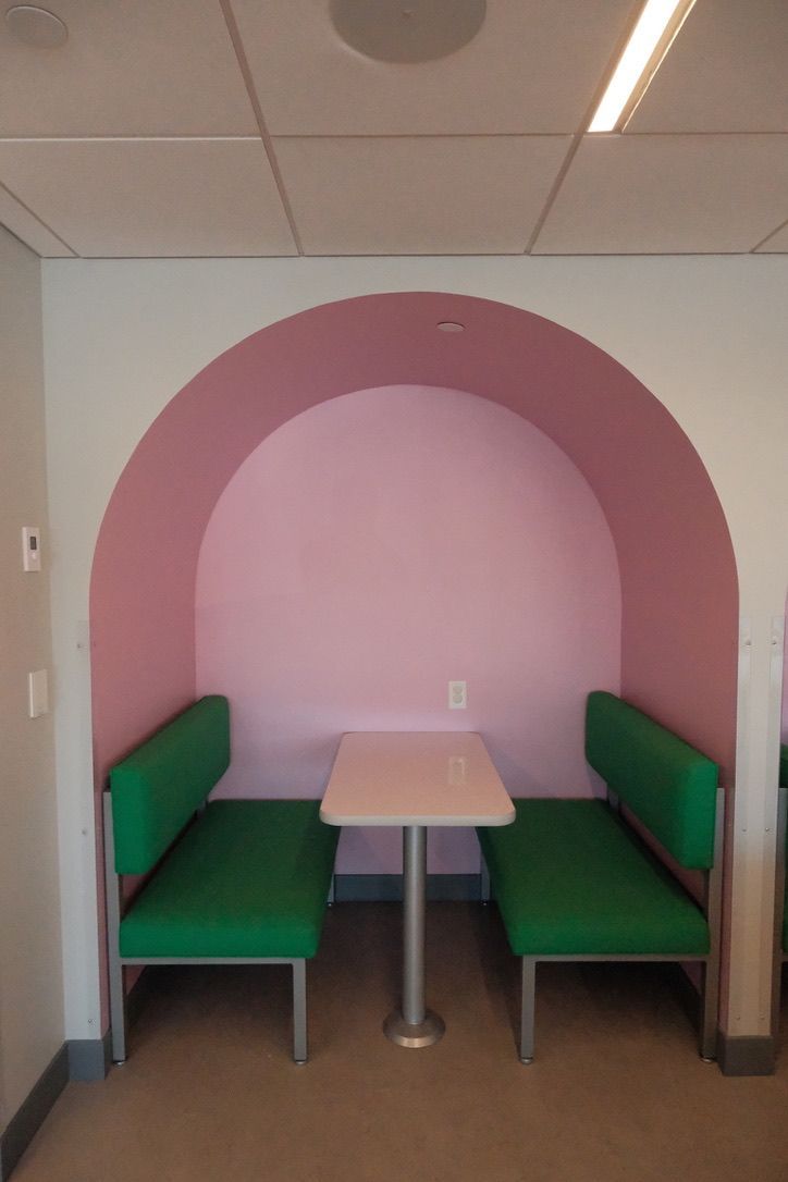 A pink and green room with a table and benches