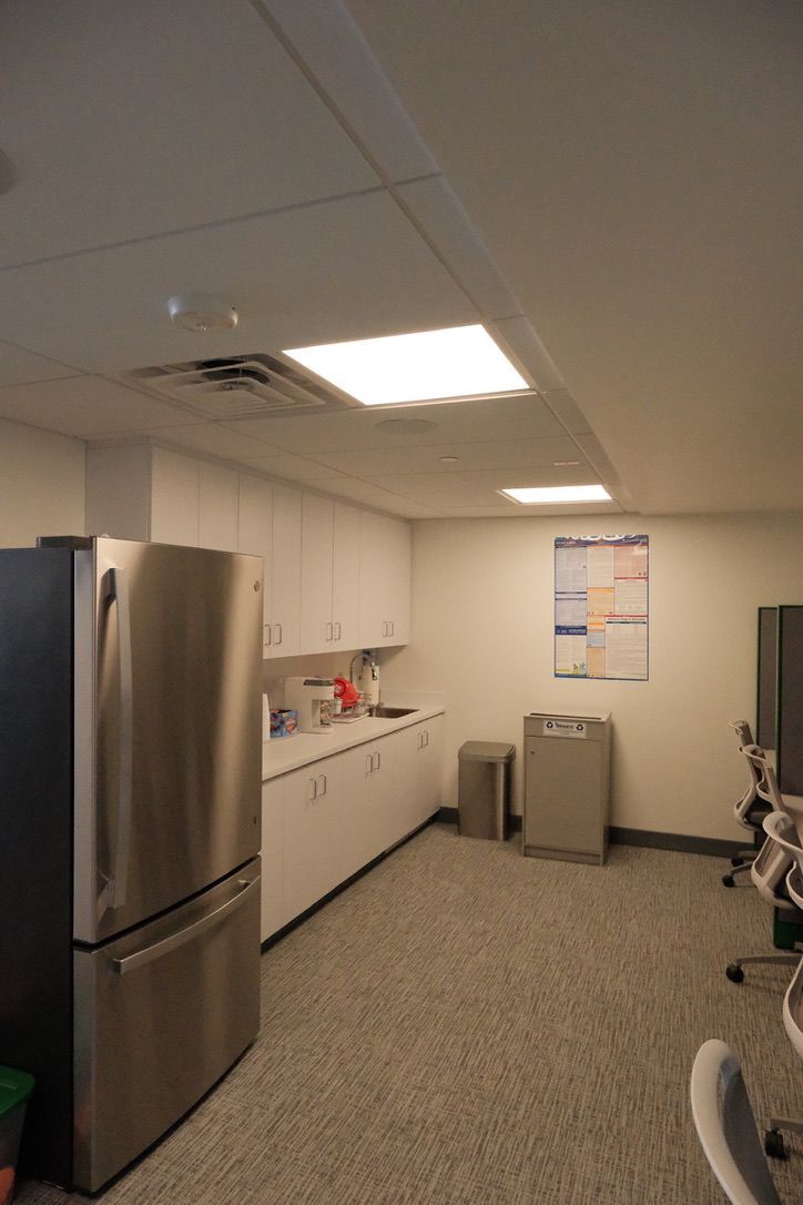 A kitchen with a refrigerator and a trash can