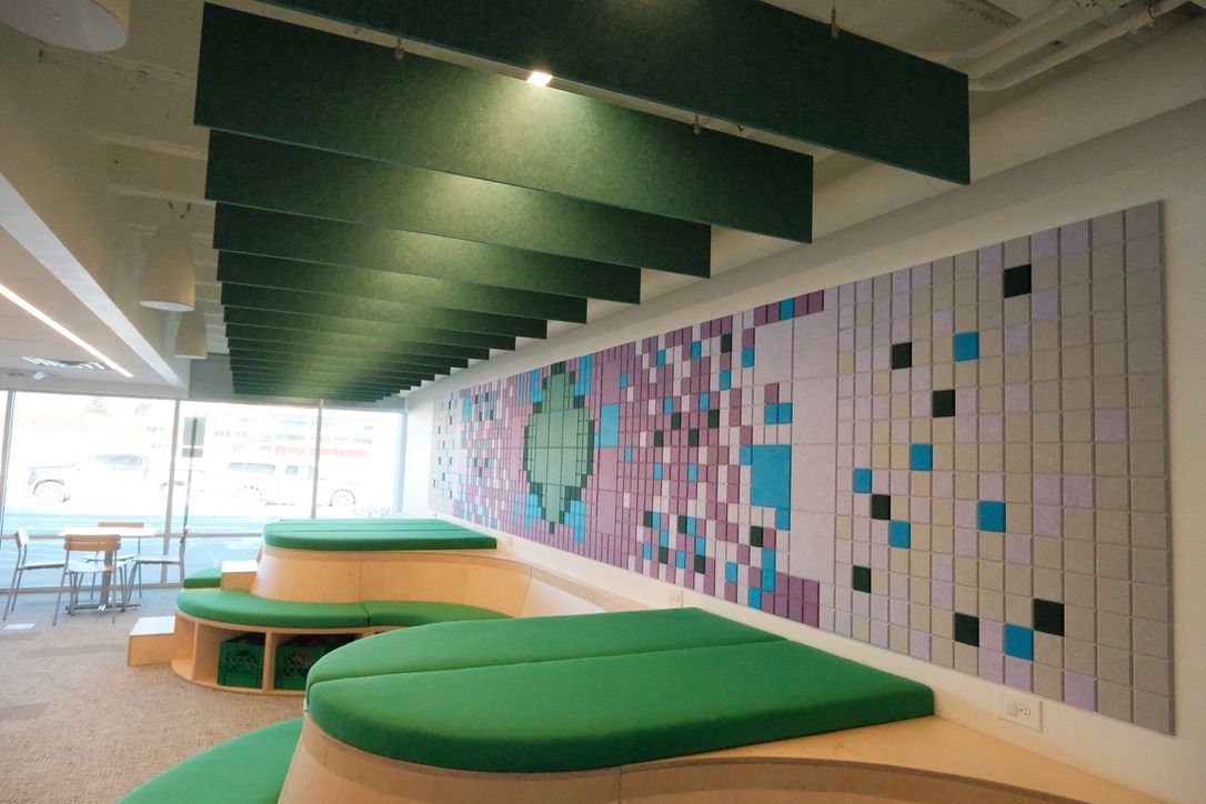 A room with green benches and a painting on the wall.