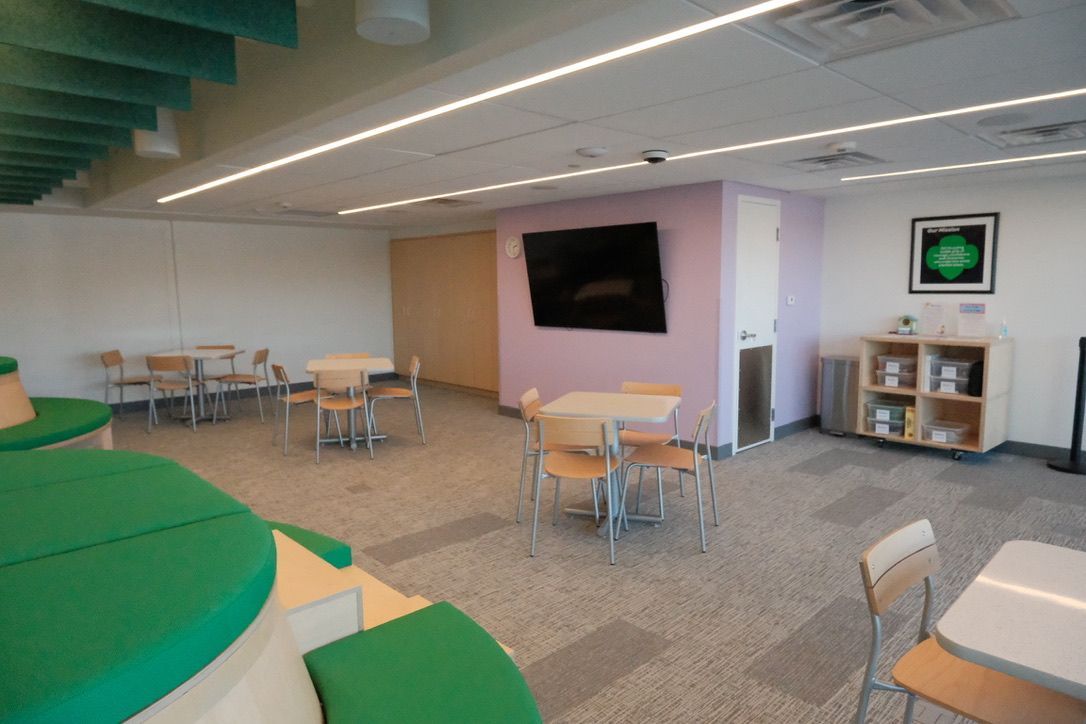 A room with tables and chairs and a television on the wall