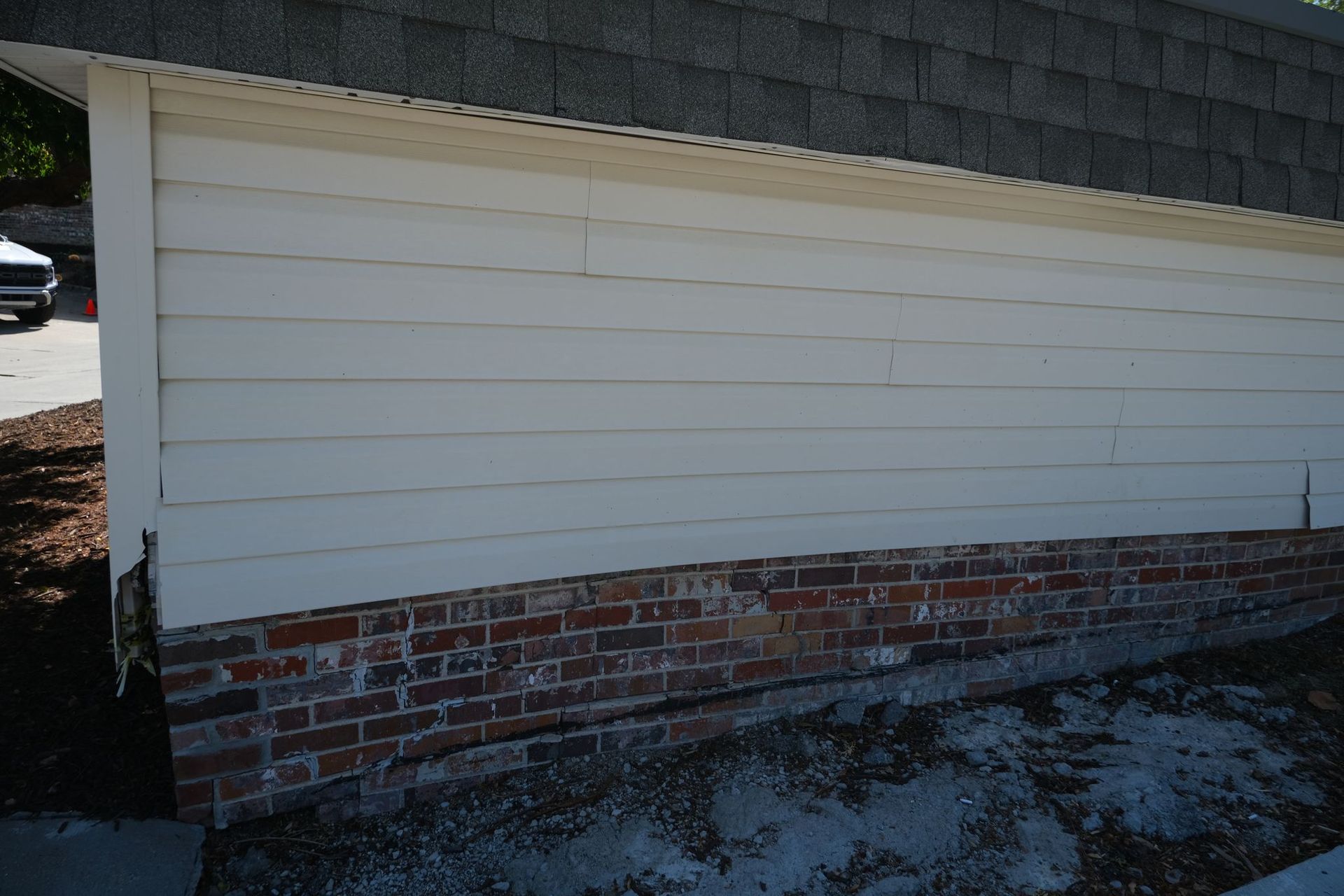 White siding over brick base on building exterior.