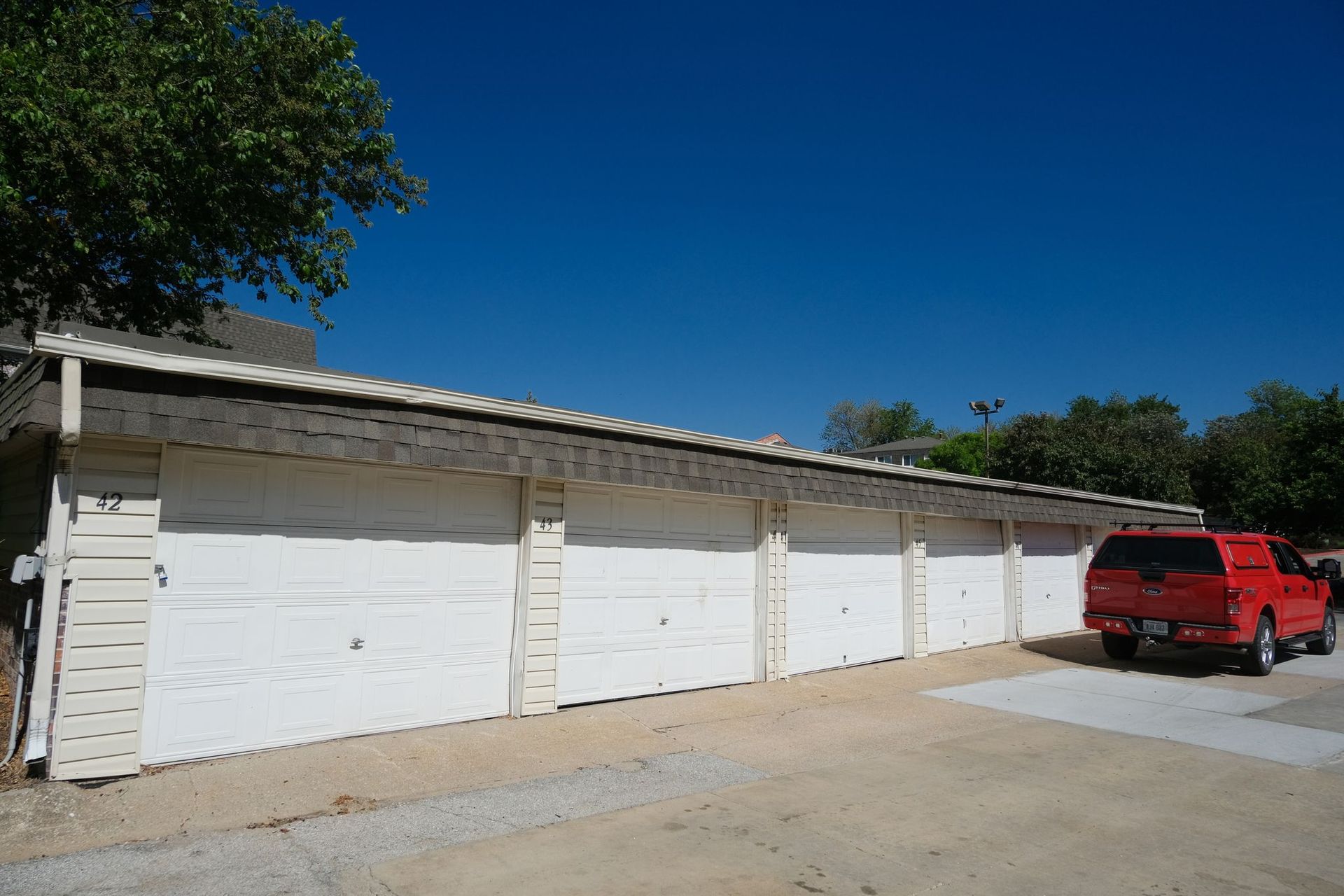 White garage doors with a red truck parked next to them, under a blue sky.
