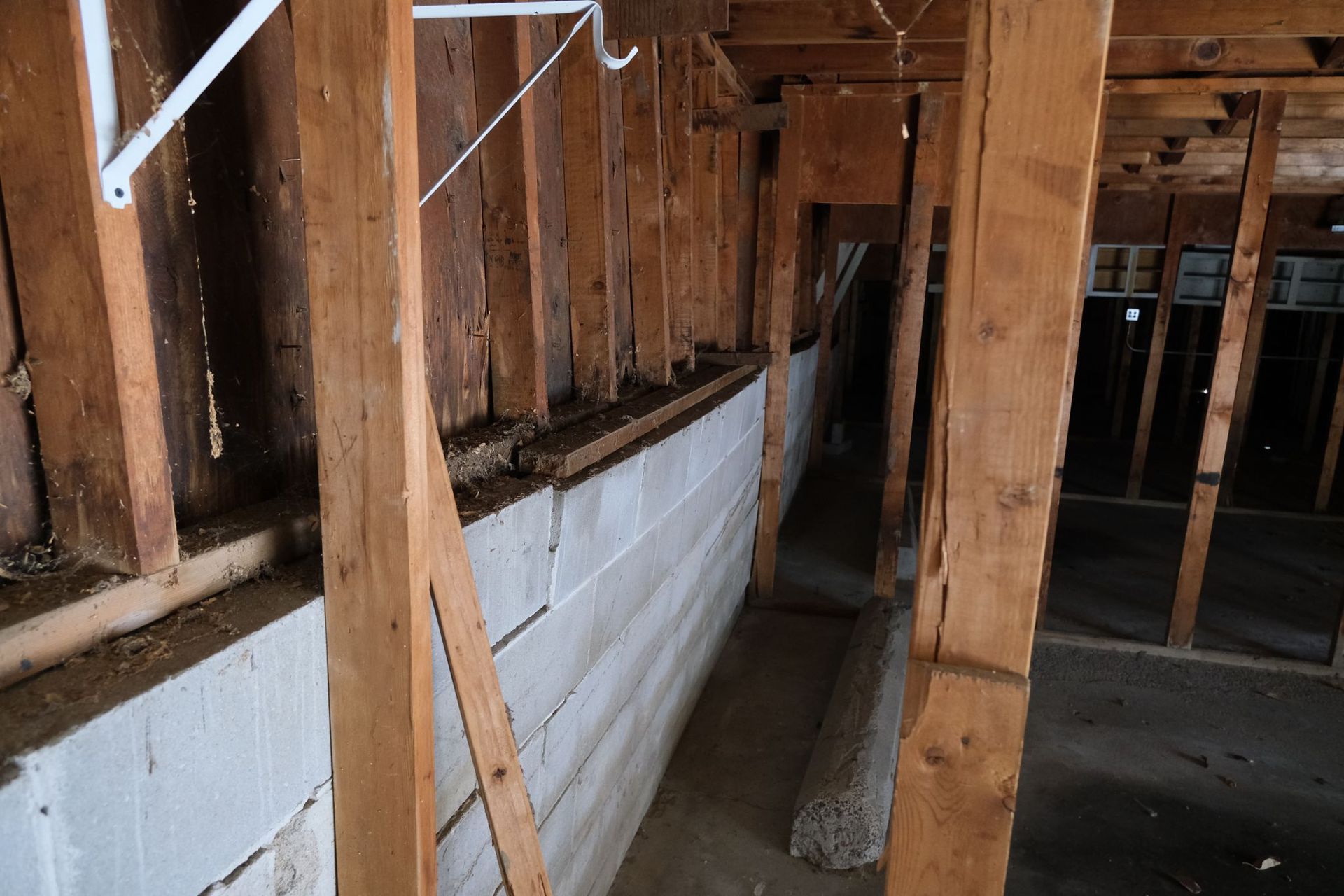 Interior view of a building's wall. Exposed wooden beams and white painted brick.