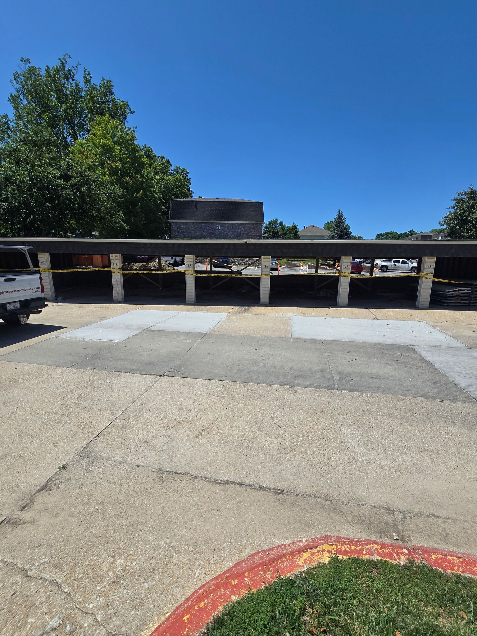 Open-air parking shelter with concrete pillars, under a clear blue sky.