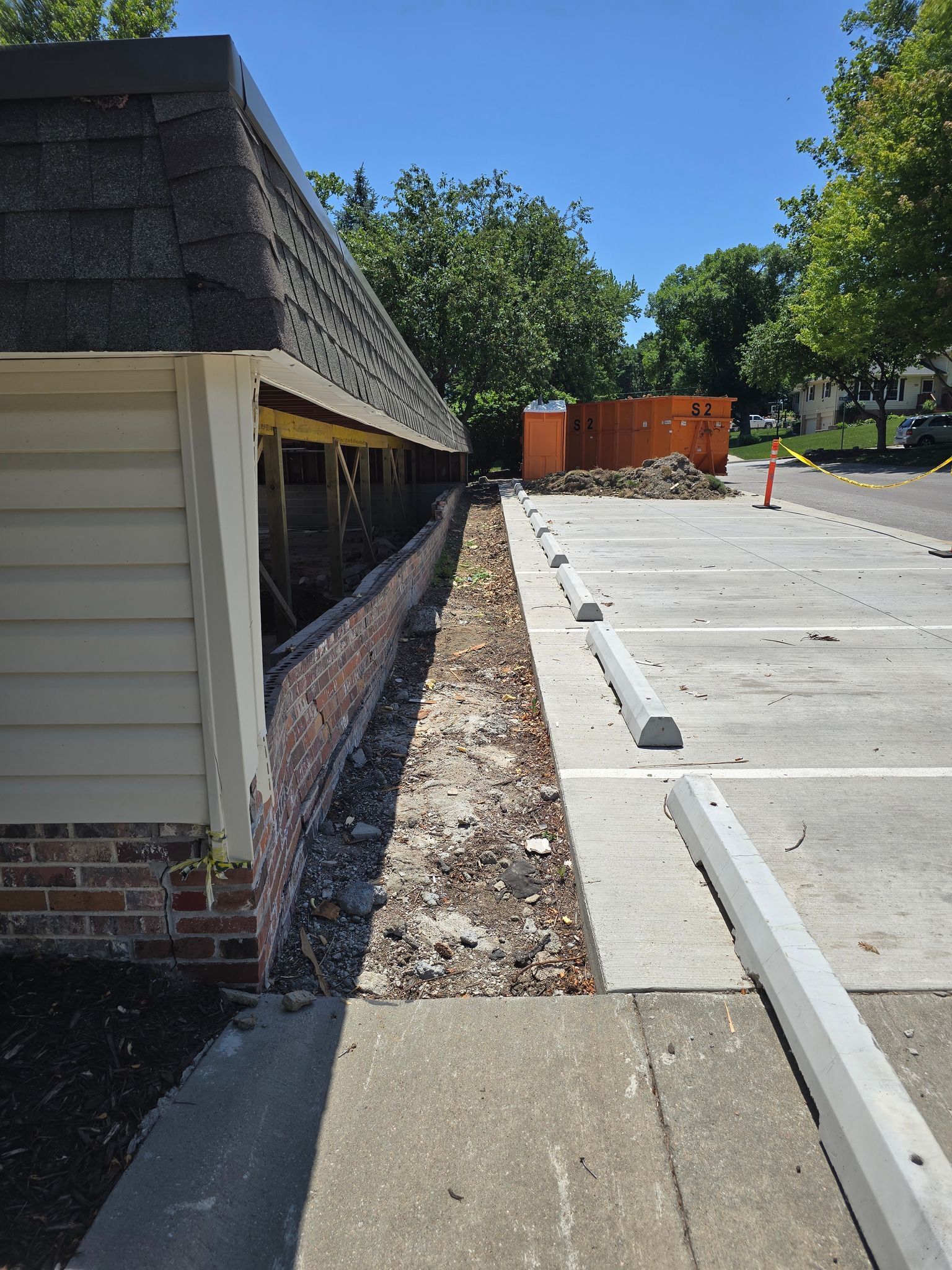 Construction site: Brick wall exposed next to a building and parking lot with debris.