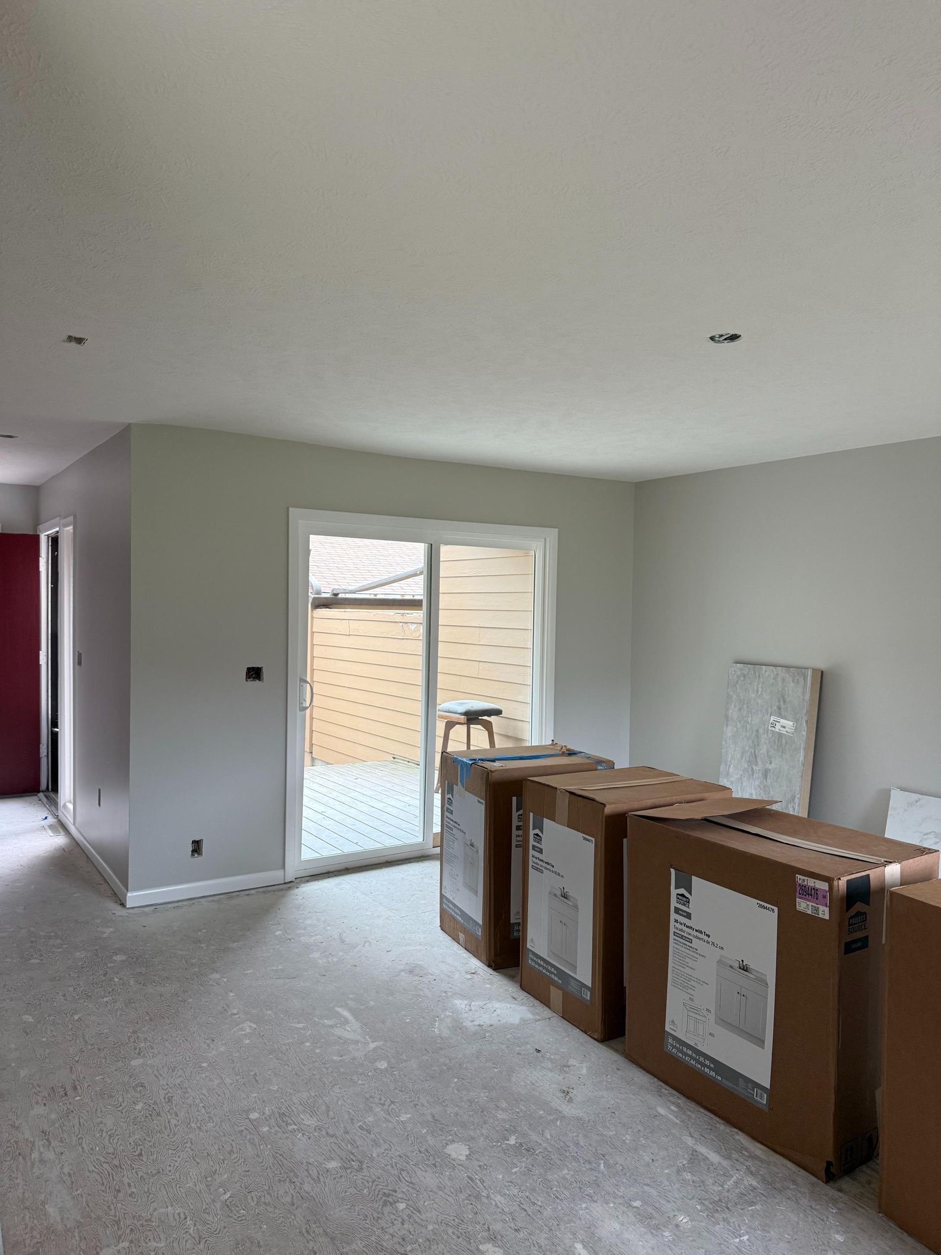 A room with cardboard boxes, a sliding door, and a red door.