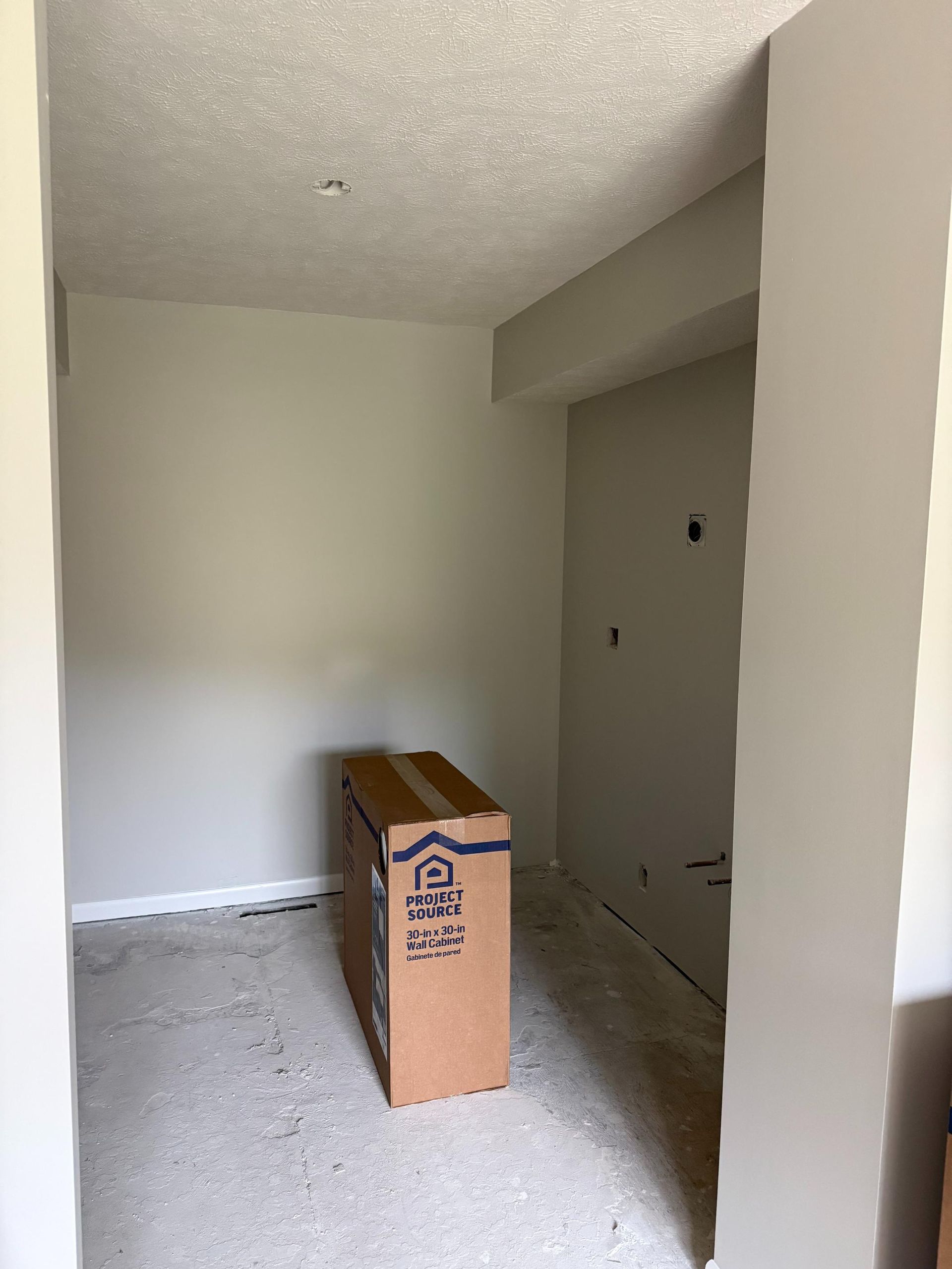 Empty room with gray walls and a cardboard box. Construction is in progress.
