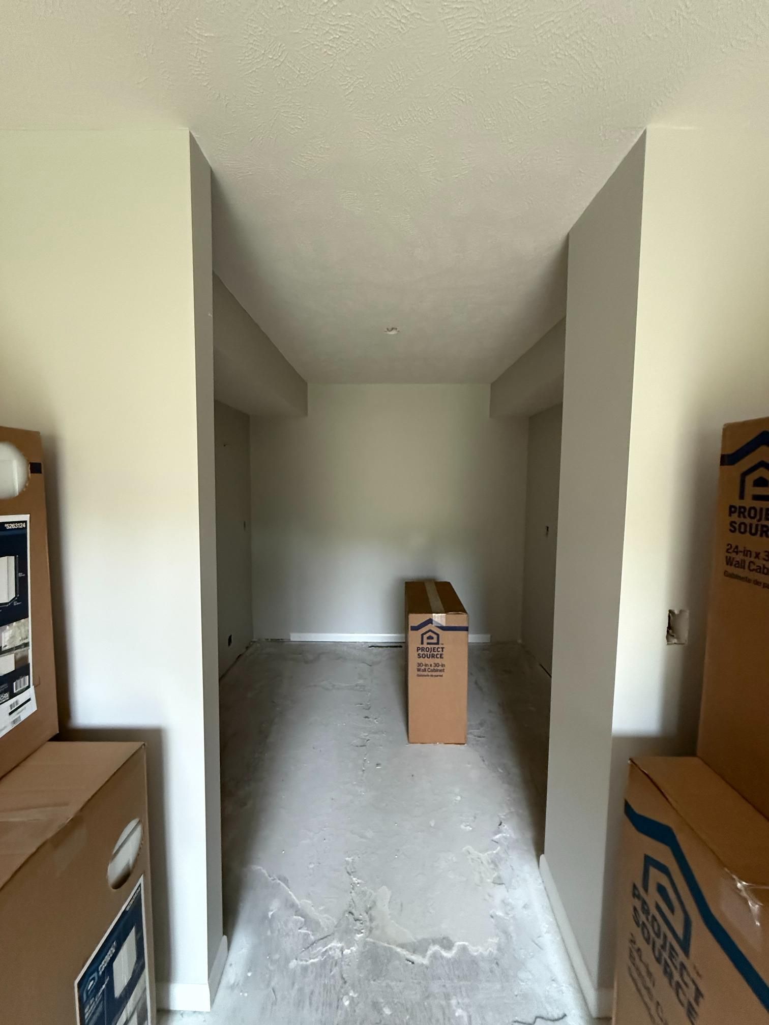 Hallway with boxes, unfinished walls, and a cardboard box.
