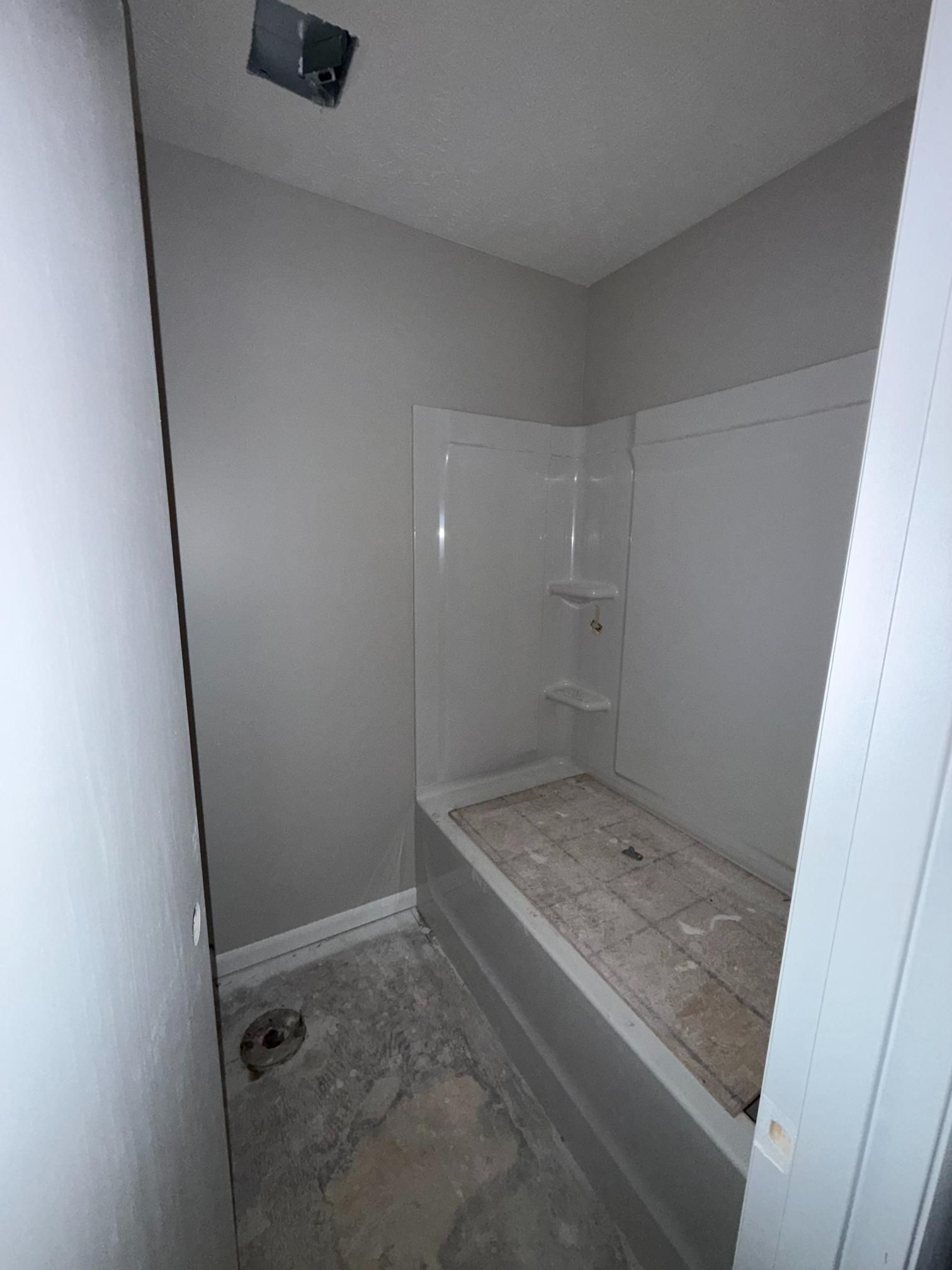 Small, empty bathroom with a white bathtub and walls, under construction.