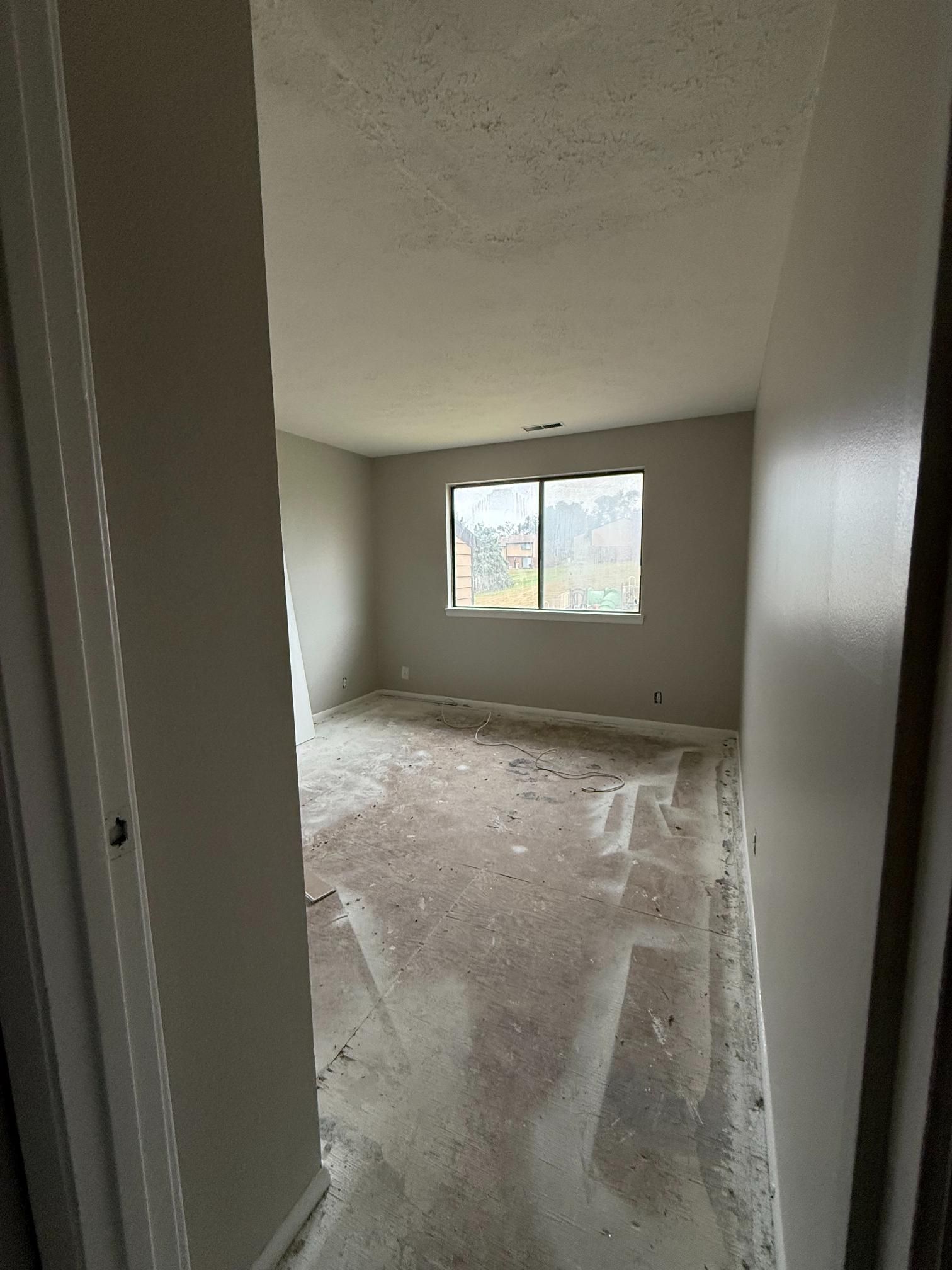 View into a room with wet flooring, a window, and freshly painted walls.
