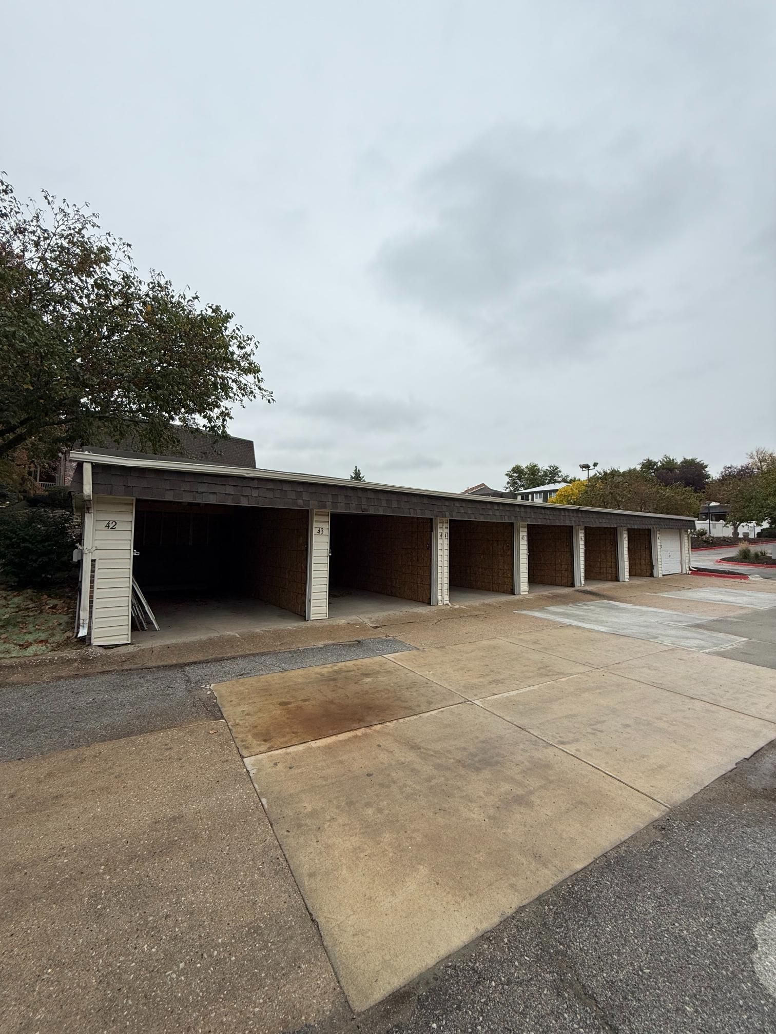 Row of empty garage bays under cloudy sky. Concrete ground in front.