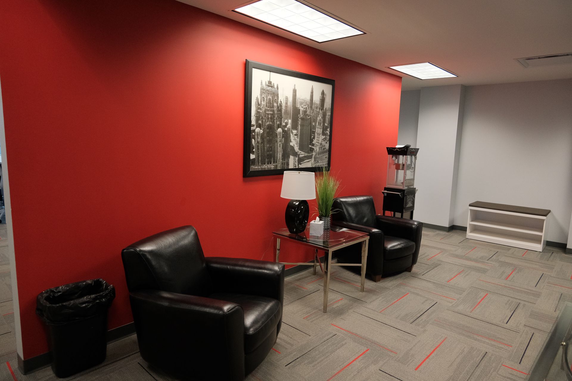 A waiting room with two chairs a table and a picture on the wall.