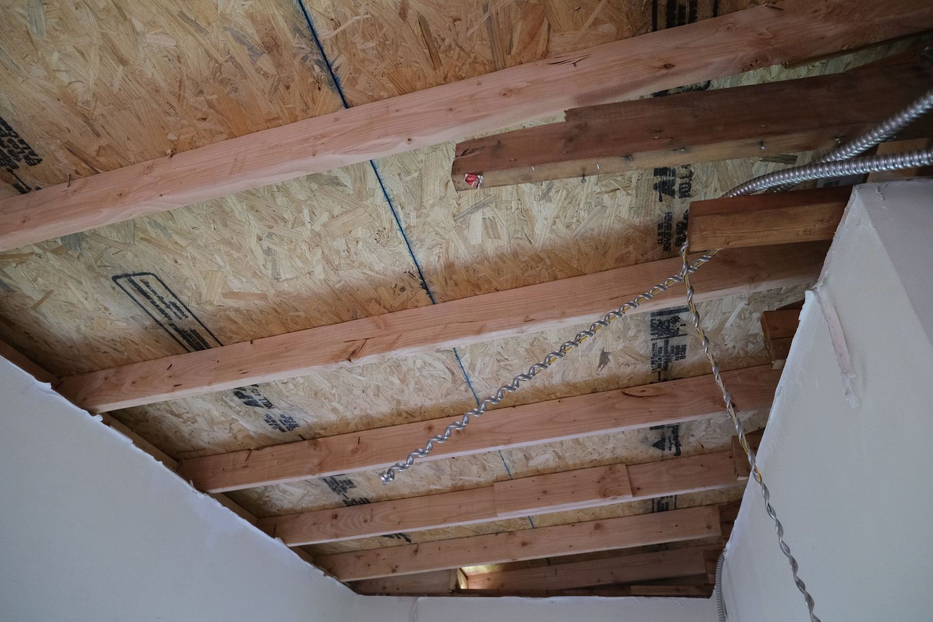 View of a wood ceiling with exposed beams and sheathing. Chains hang down.